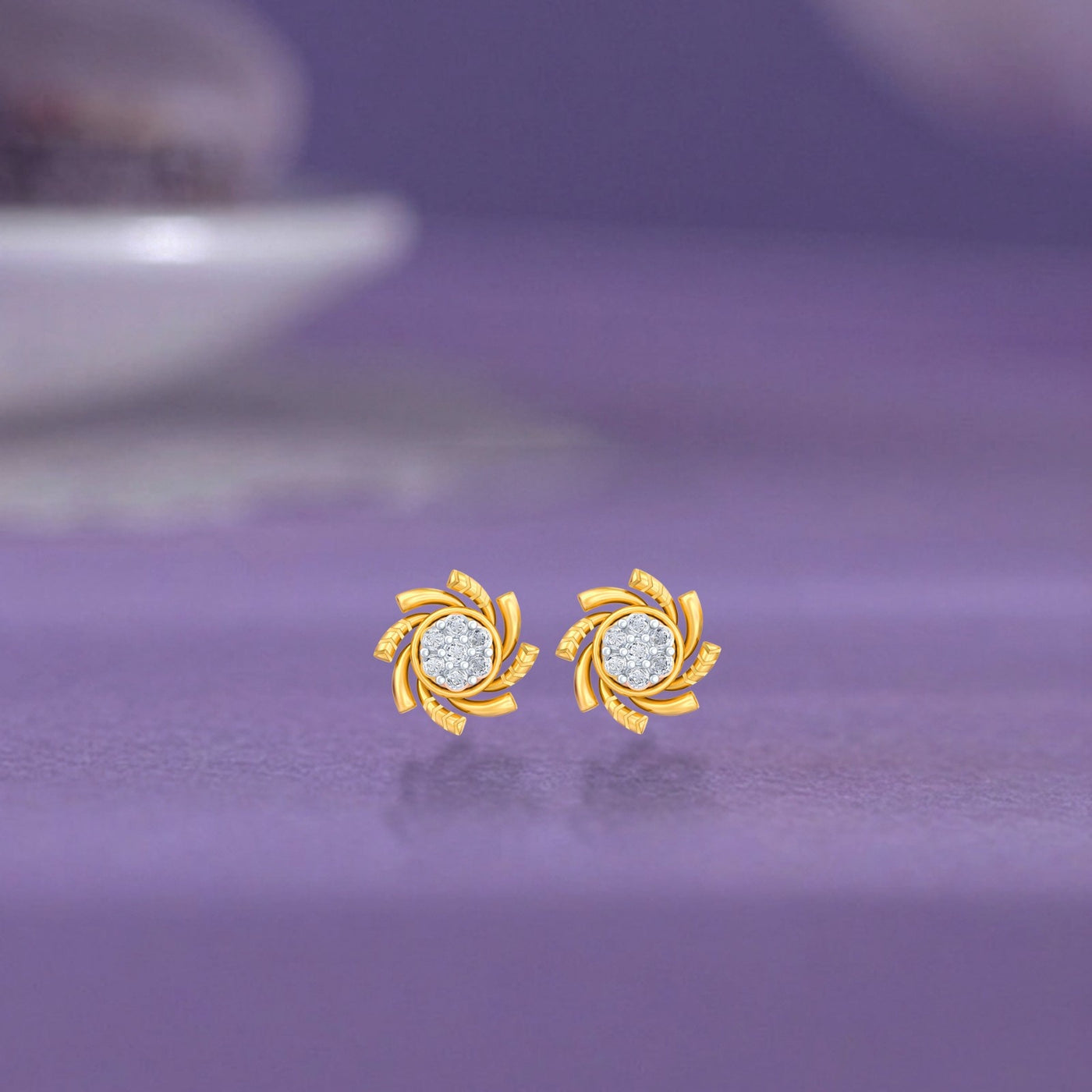 Gold and diamond stud earring with floral-shaped on a blue surface.