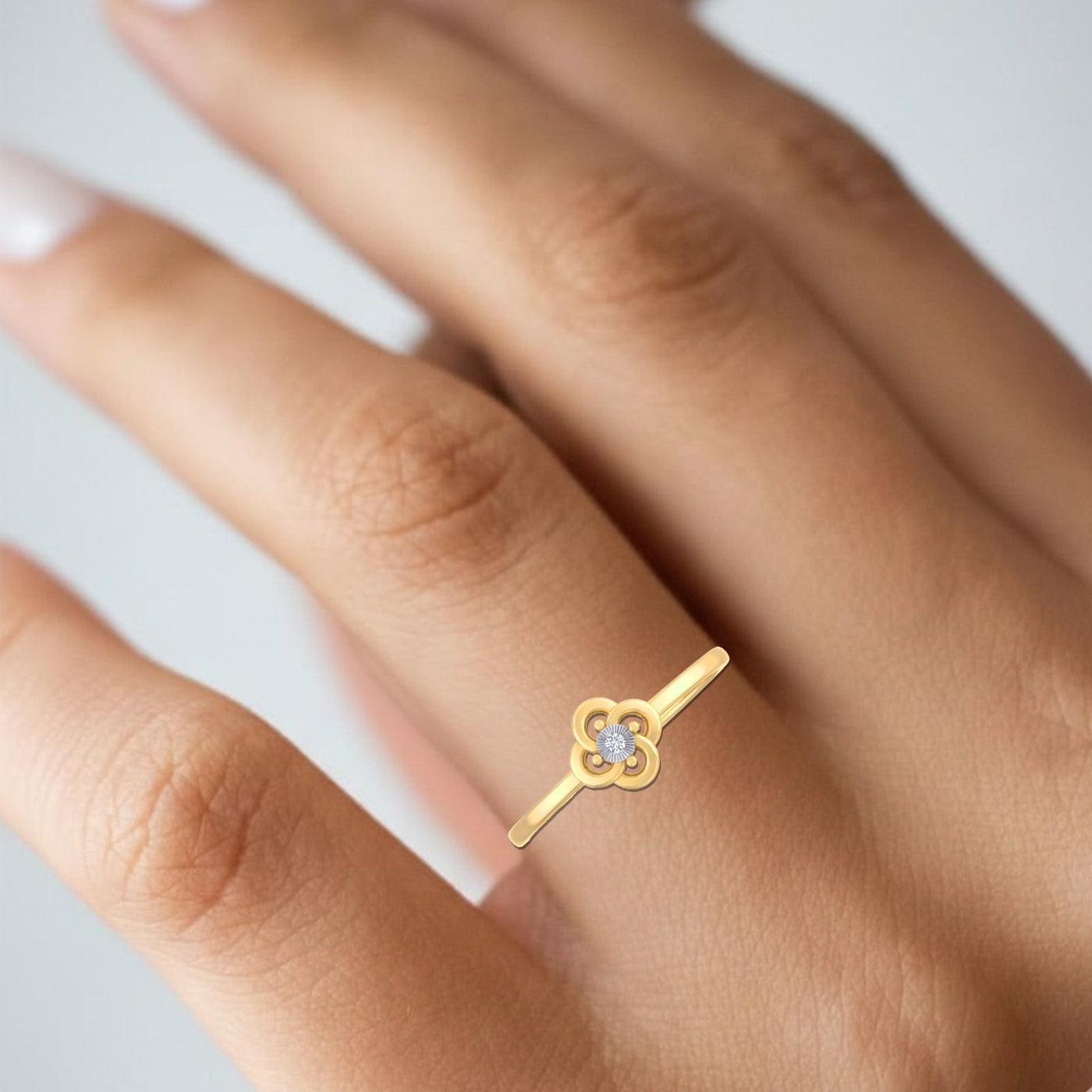 Gold ring with a heart and key design on a person's finger against a neutral background