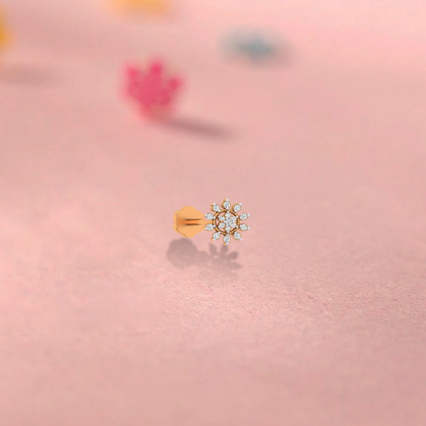 Yellow gold and diamond stud nose pin  with clear gemstones on a pink background