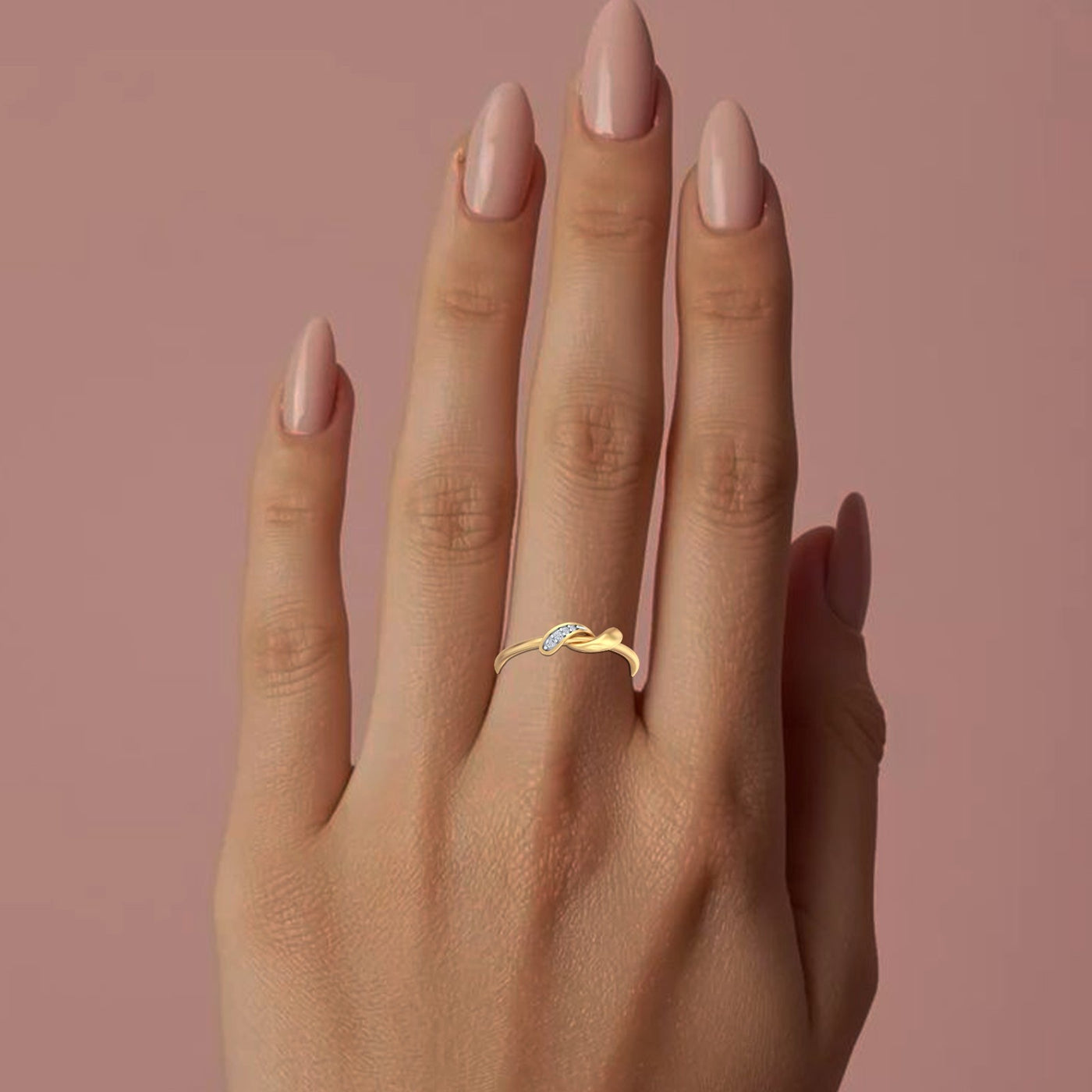 Hand wearing a gold ring with a blue gemstone against a pink background