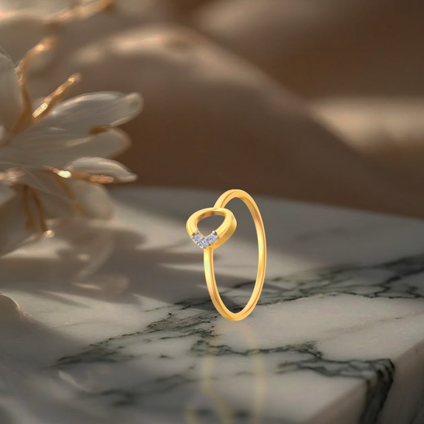 A delicate yellow gold ring standing upright on a polished marble surface