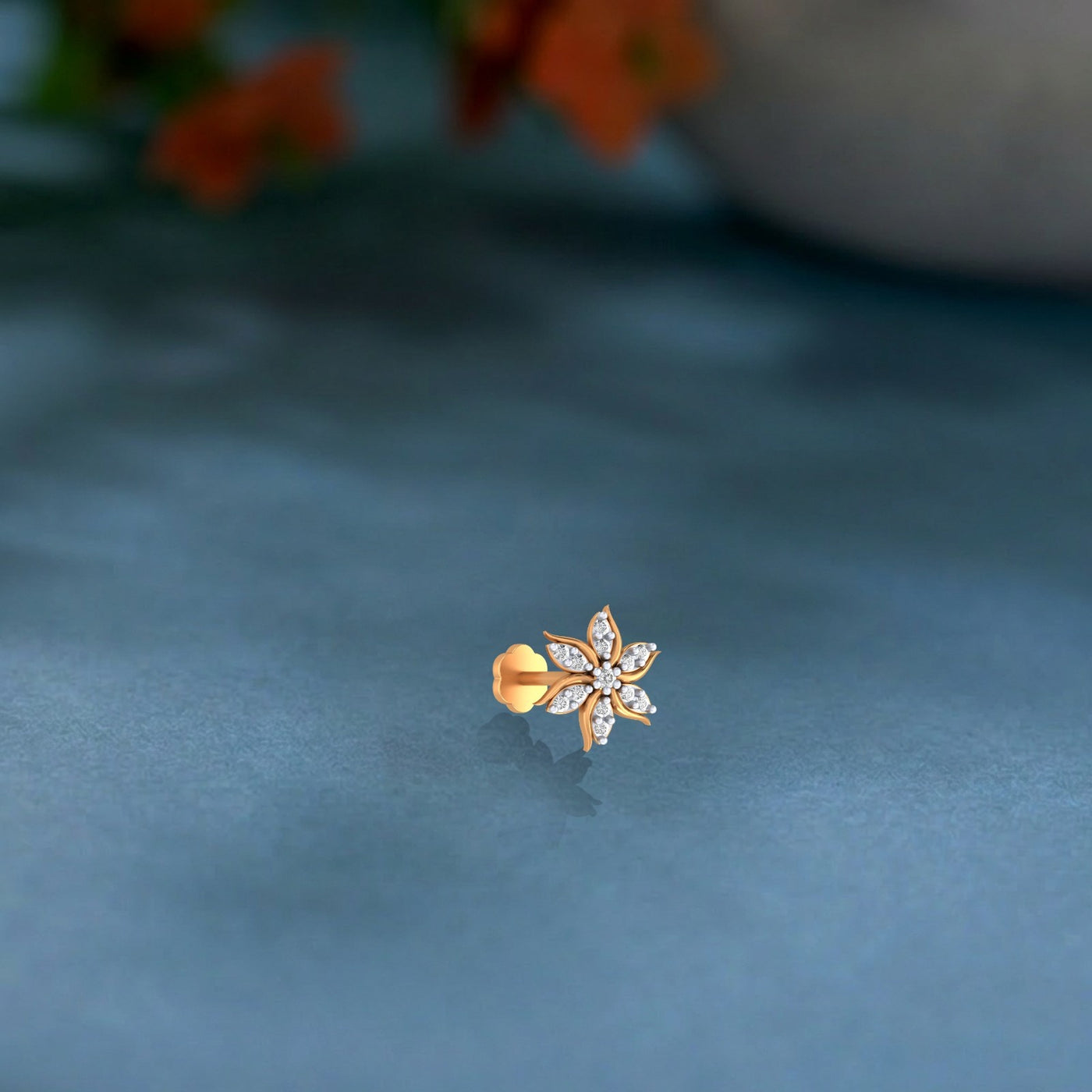 yellow Gold and diamond nose pin with floral design on a dark blue fabric background