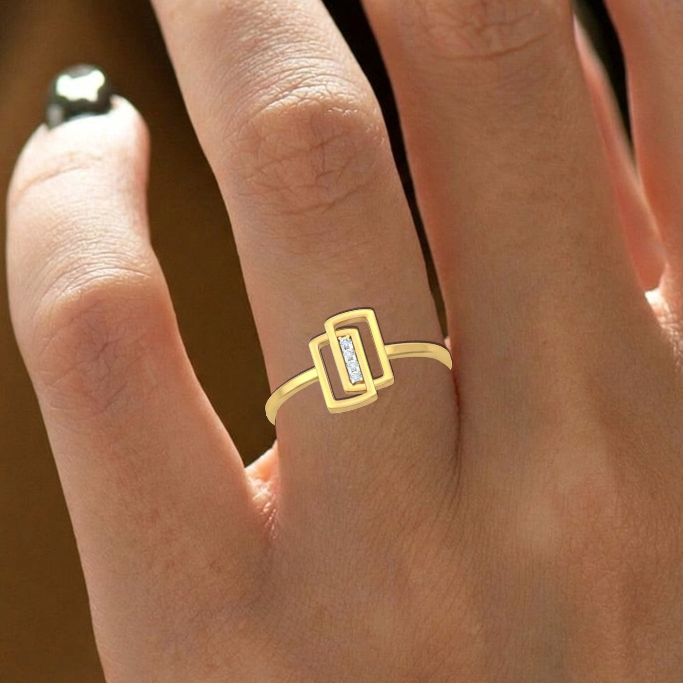 Gold ring with a diamond on a person's finger against a blurred background