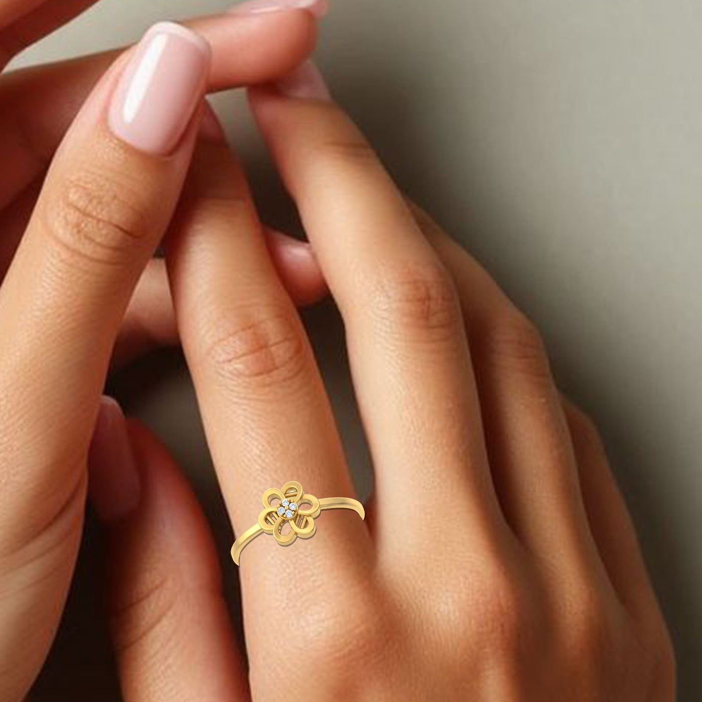 Gold ring with a diamond on a person's finger against a neutral background