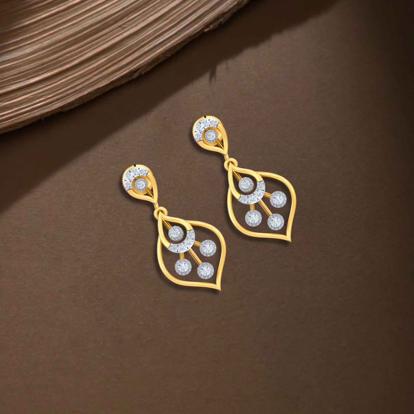 Gold and diamond drop earring on a brown background.