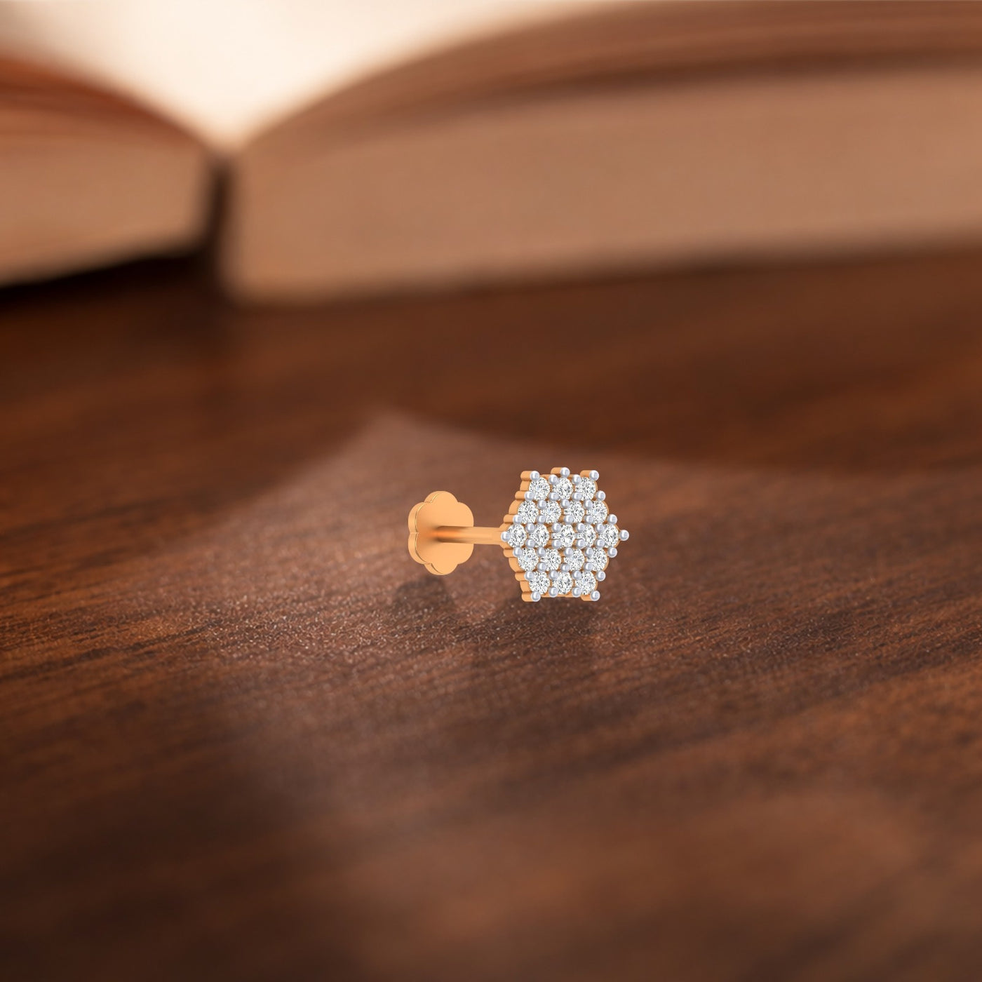 yellow gold and diamond stud nose pin on a wooden surface with a blurred background