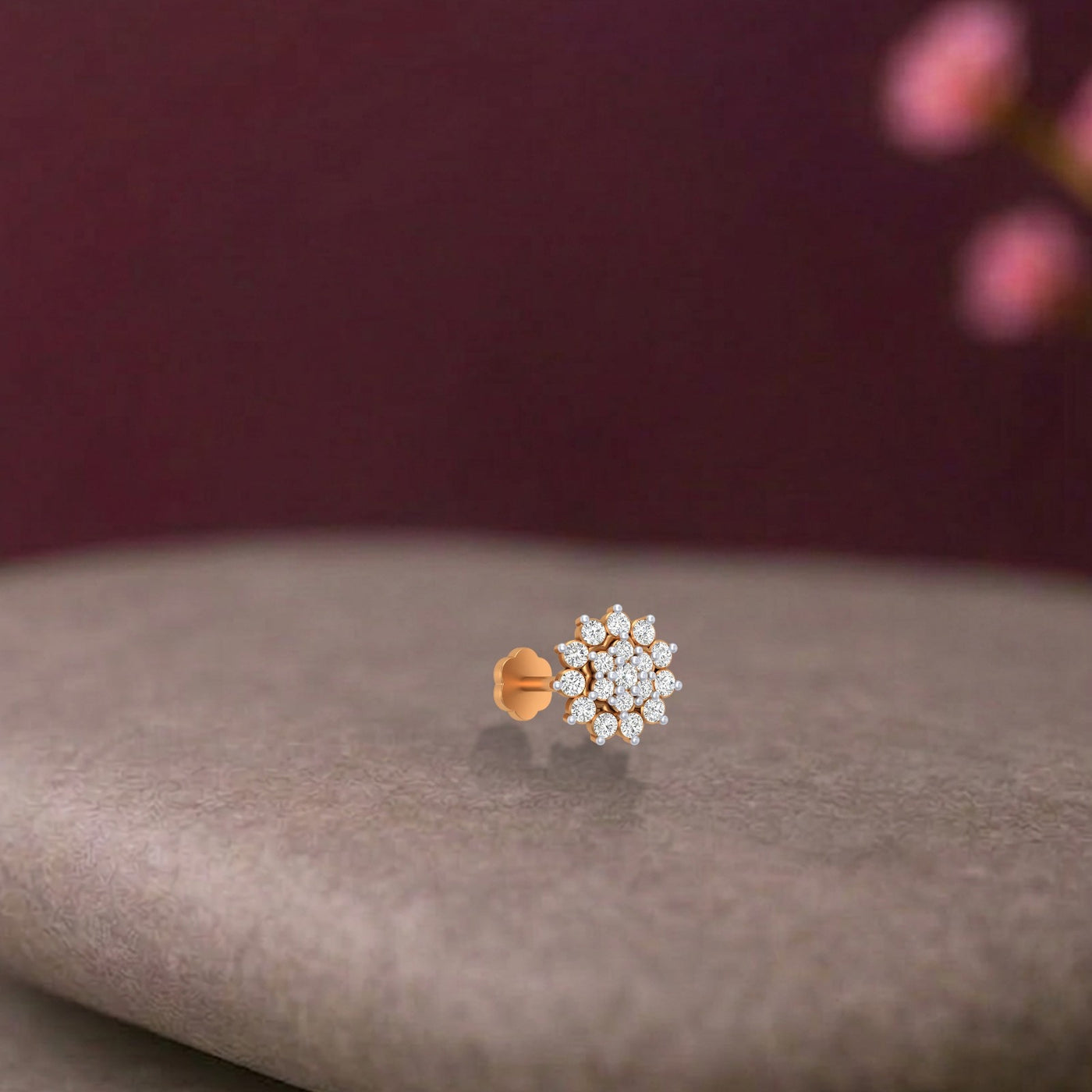 yellow gold and diamond stud nose pin on a gray surface with a blurred background