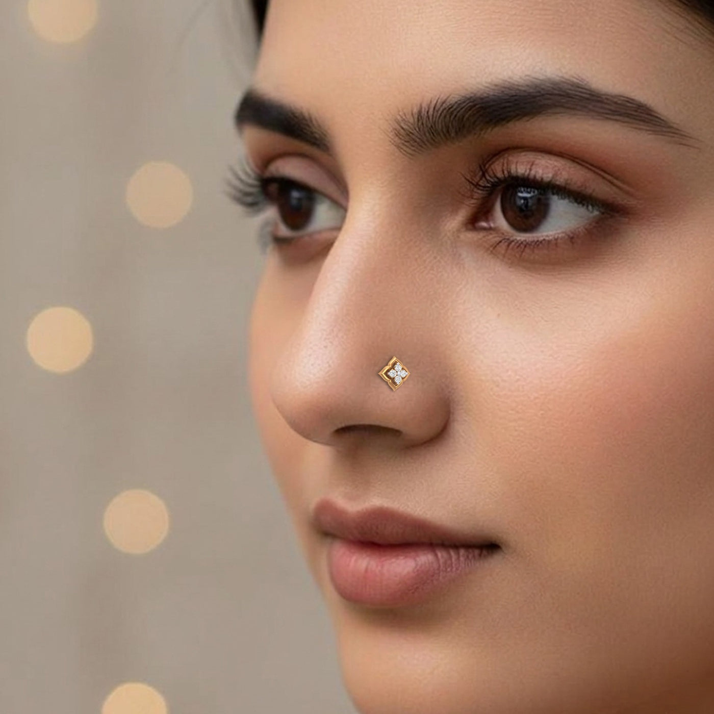 Close-up of a woman's face with a diamond nose pin against a beige background with gold dots.
