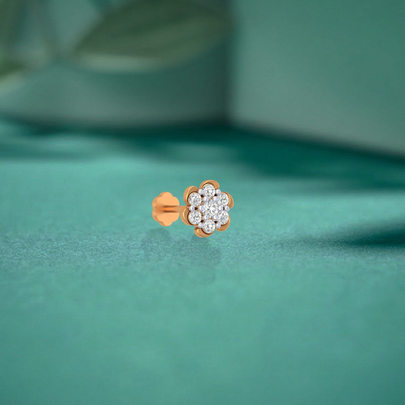 yelllow gold and diamond stud nose pin with diamonds on a teal fabric background