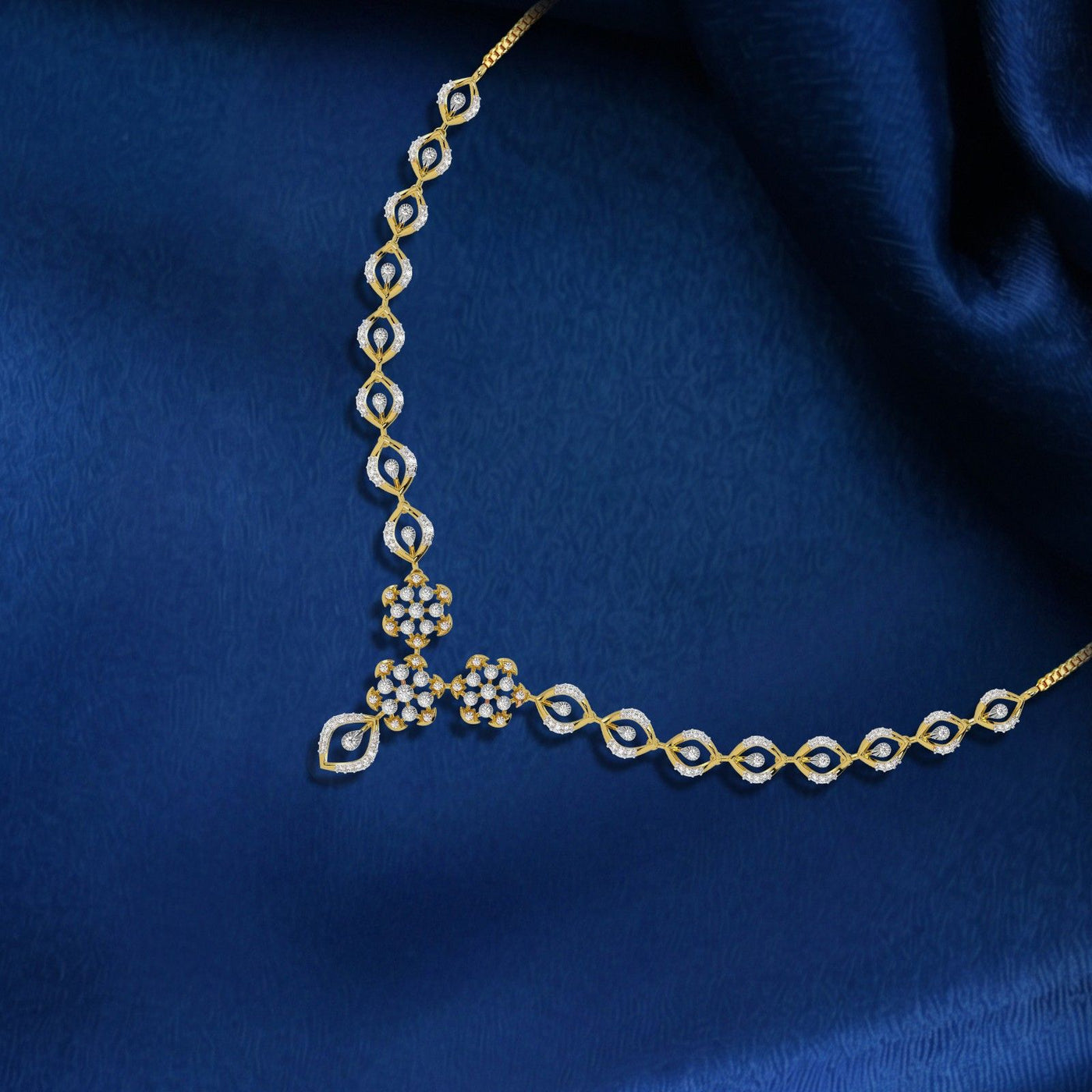 Gold necklace with diamond accents on a blue fabric background