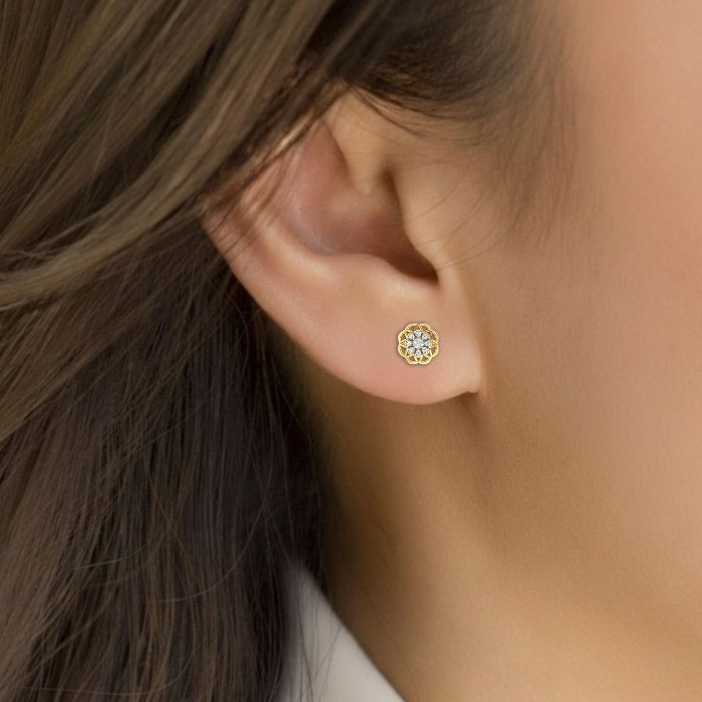 Close-up shot of a gold and diamond stud earring with floral-design.