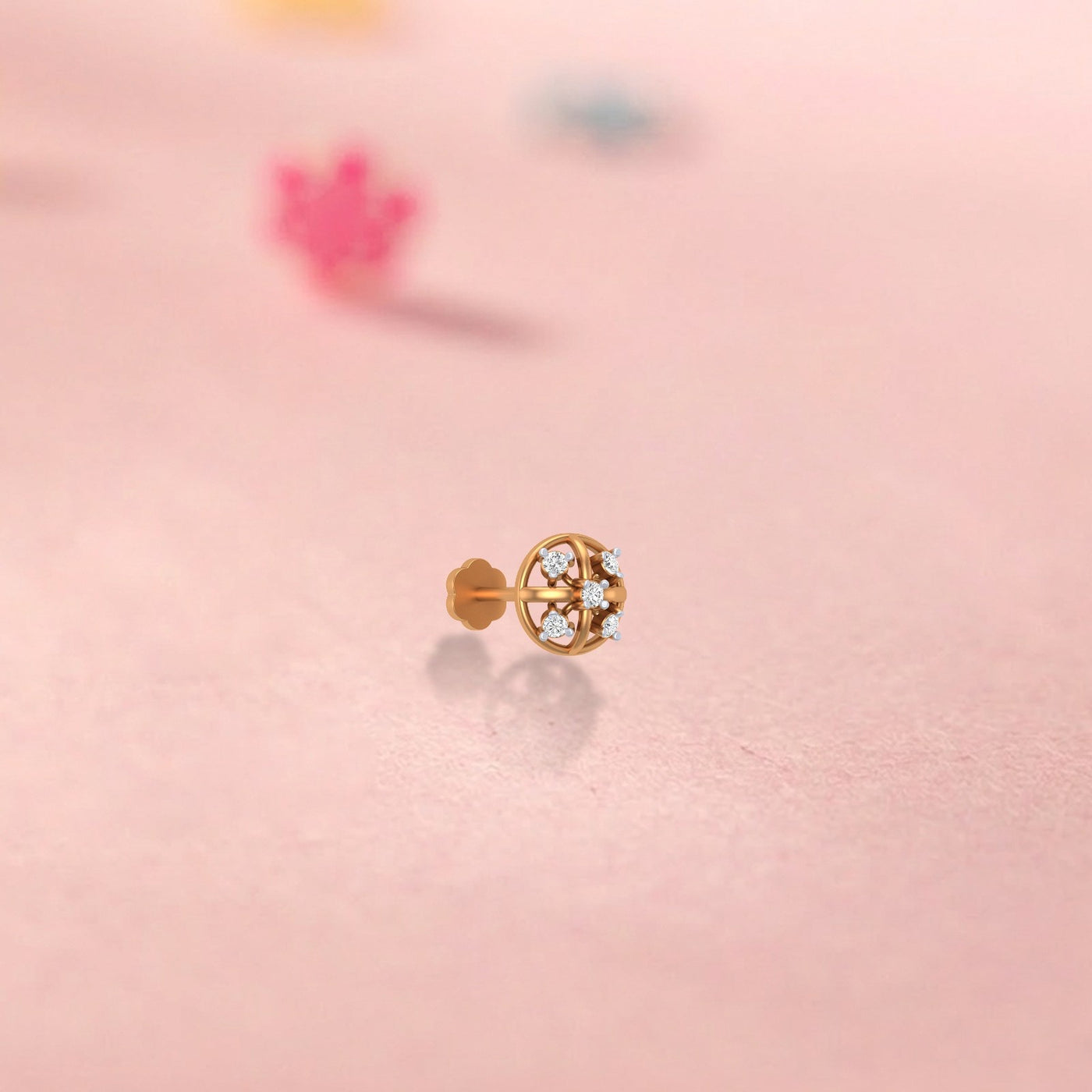 yellow gold and diamond stud nose pin on a pink background