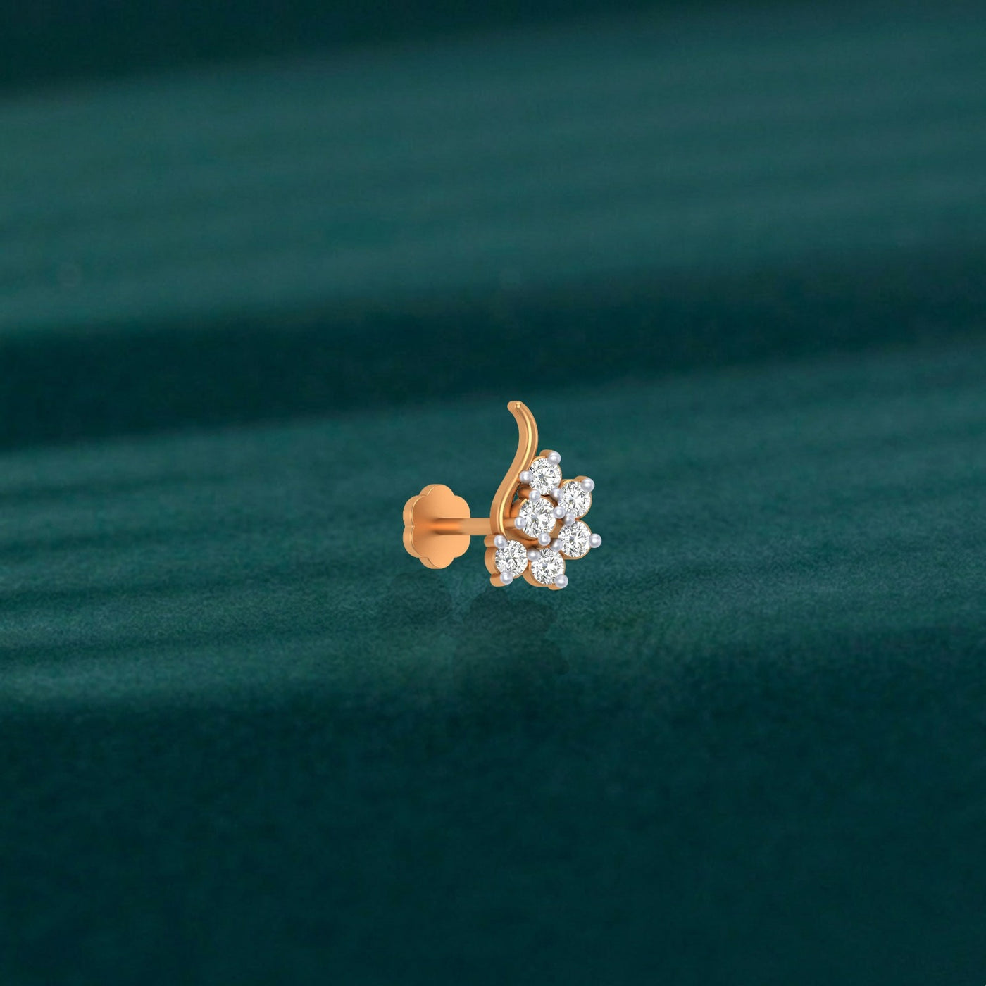 yellow gold and diamond stud nose pin on a green fabric background
