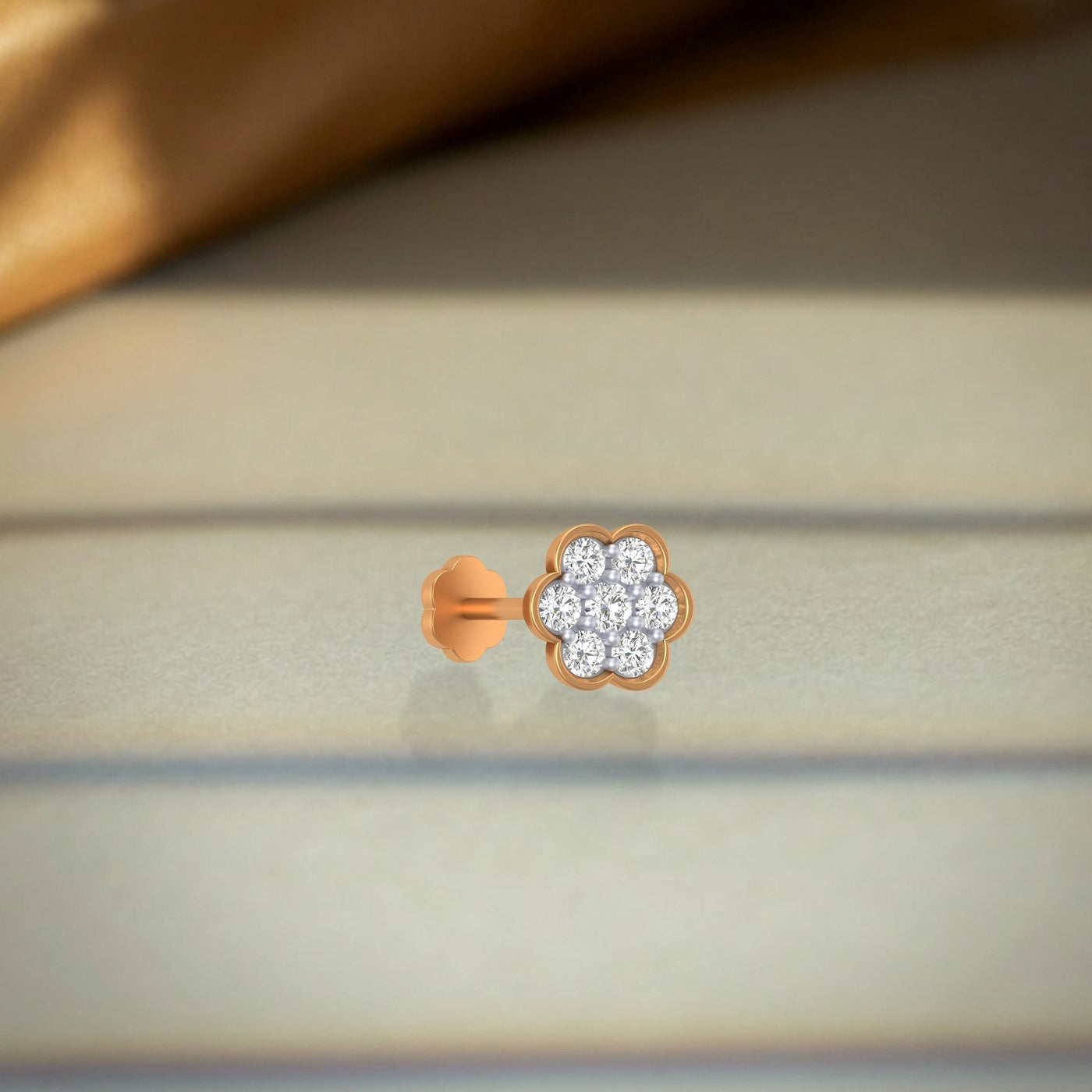 yellow gold and diamond stud nose pin with diamond accents on a neutral background