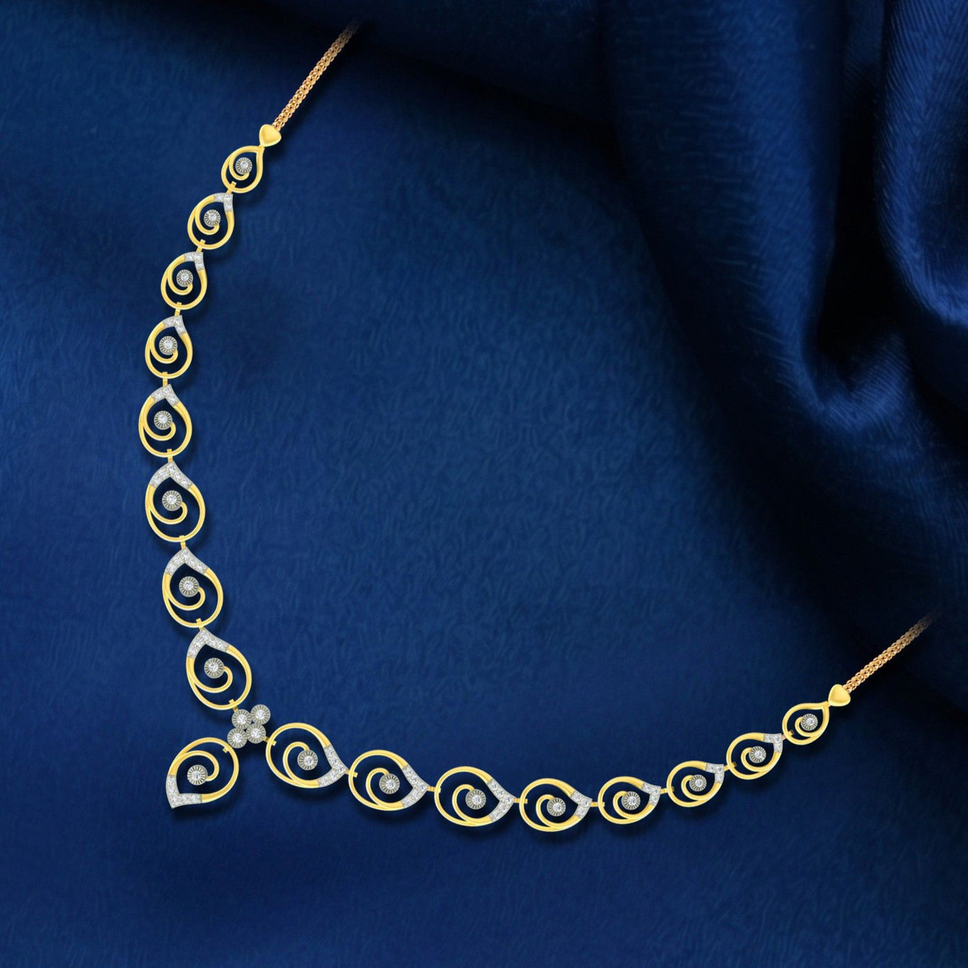Gold and diamond necklace with a series of spiral motifs and a small floral accent, displayed on a draped dark blue fabric background.
