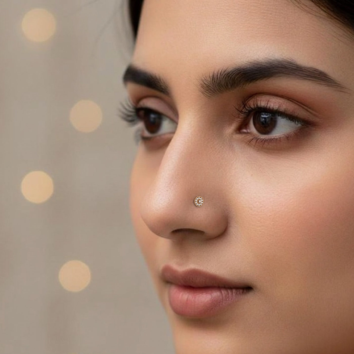 Close-up of a woman's face with a nose pin against a neutral background