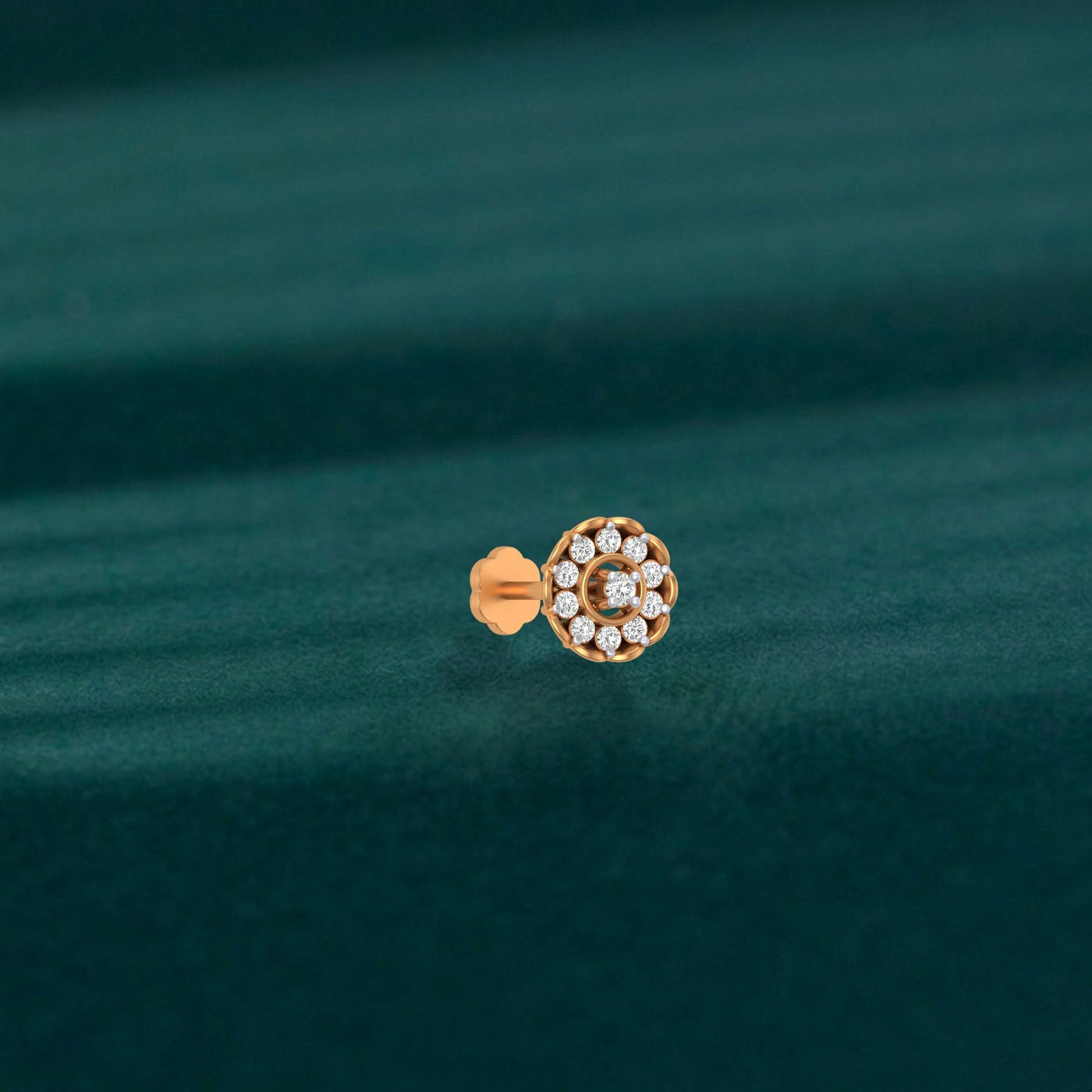 yellow gold and diamond stud nose pin with a circular design on a teal fabric background
