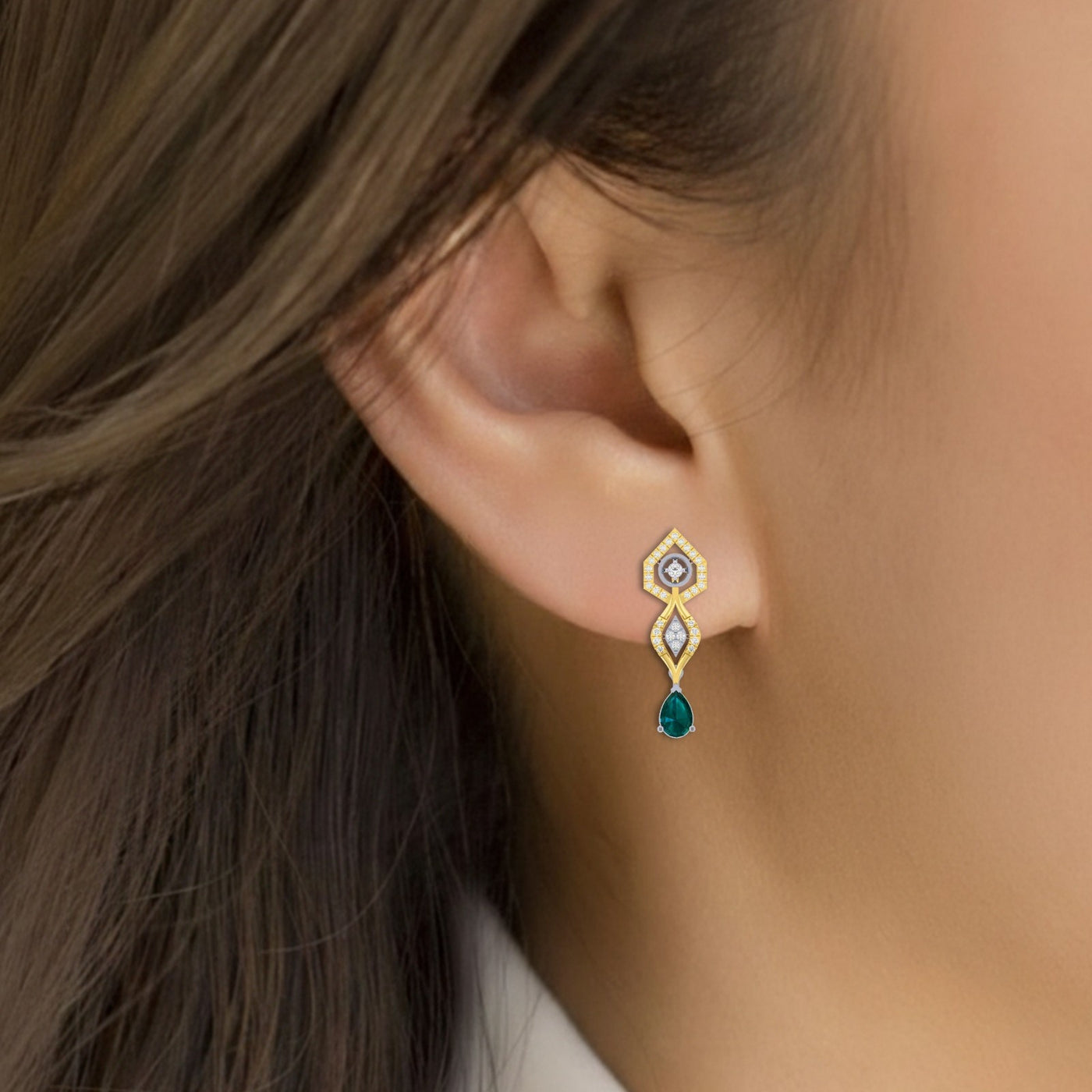 Close-up shot of a gold and diamond earrings with green gemstones.