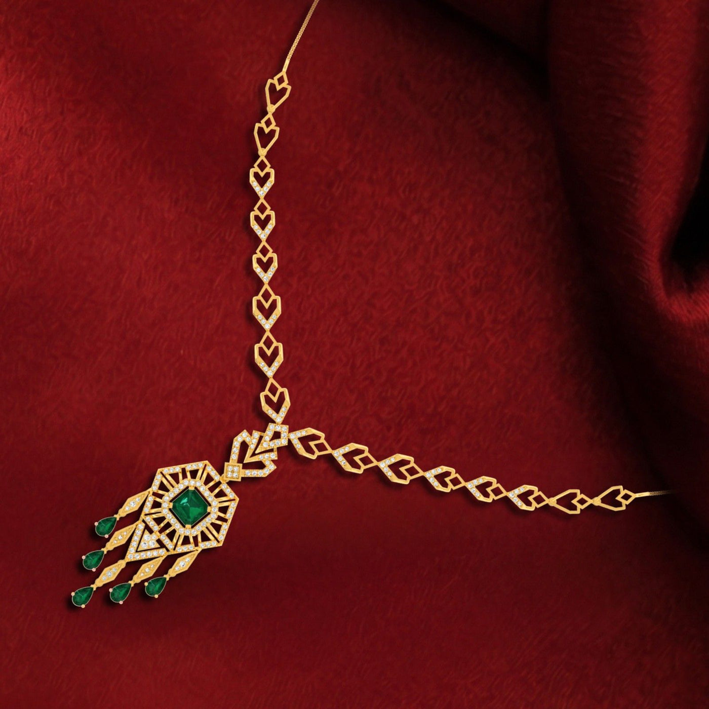 Gold and diamond necklace featuring a central green emerald, displayed on a rich red fabric background.