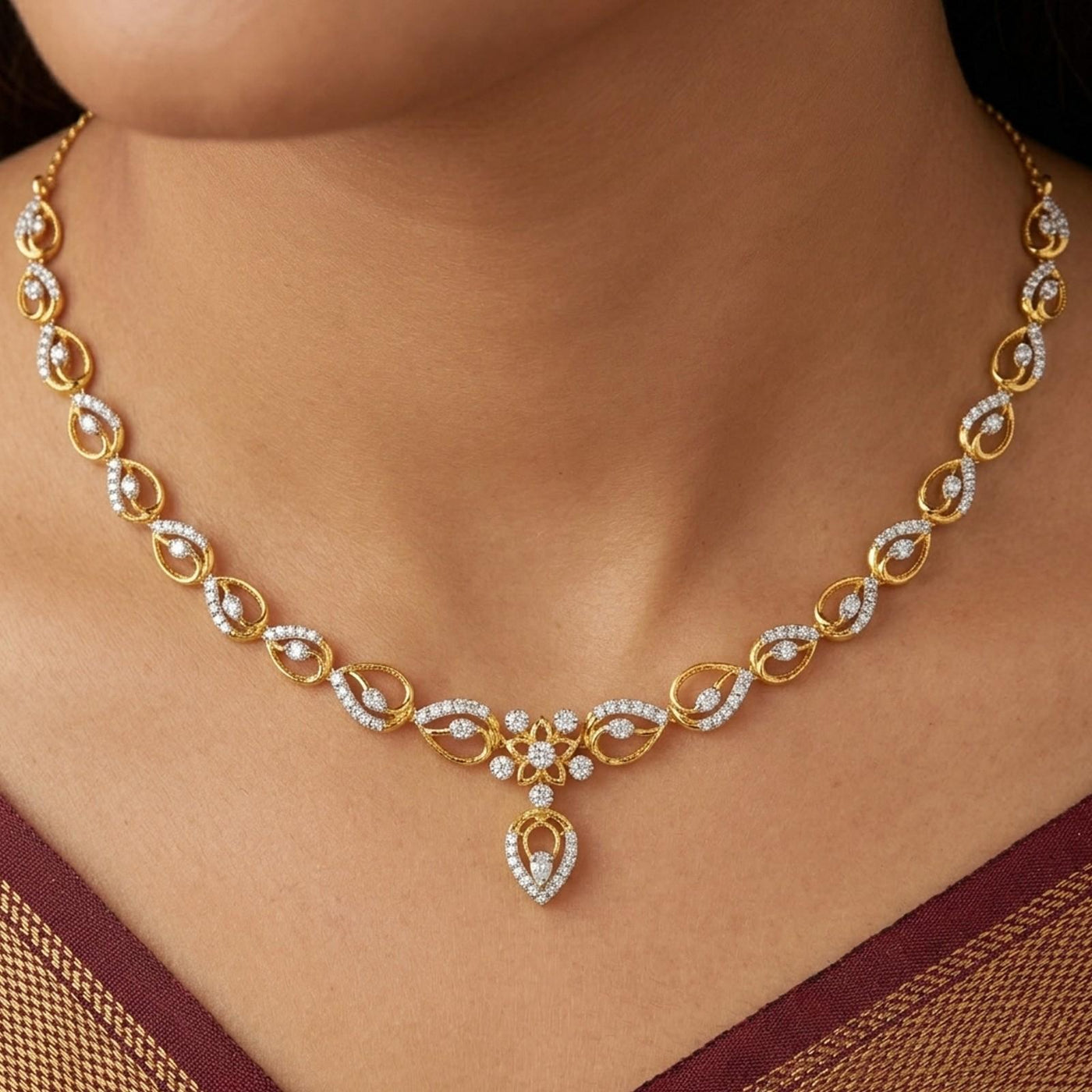 Gold and diamond necklace worn on a model's neck, featuring a teardrop-shaped.
