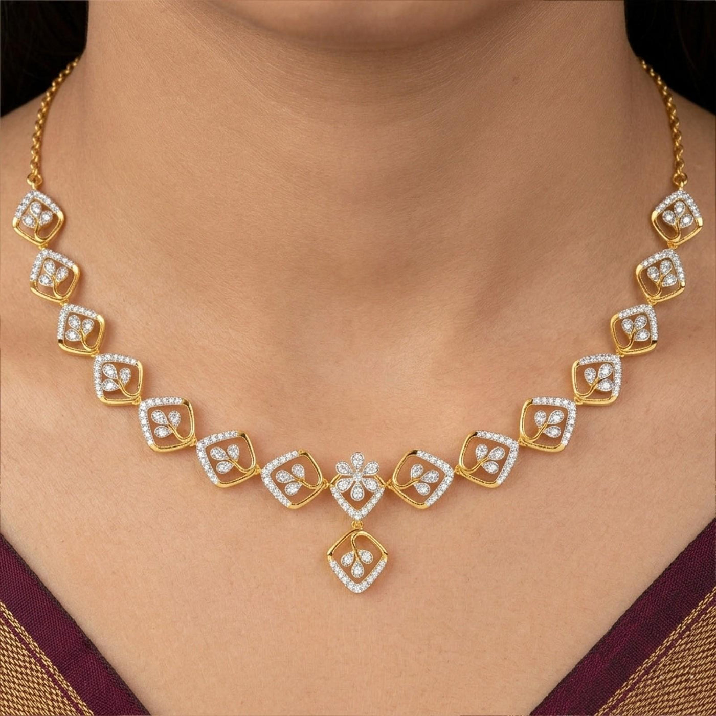 A gold and diamond necklace worn on a model's neck, featuring a central floral motif.