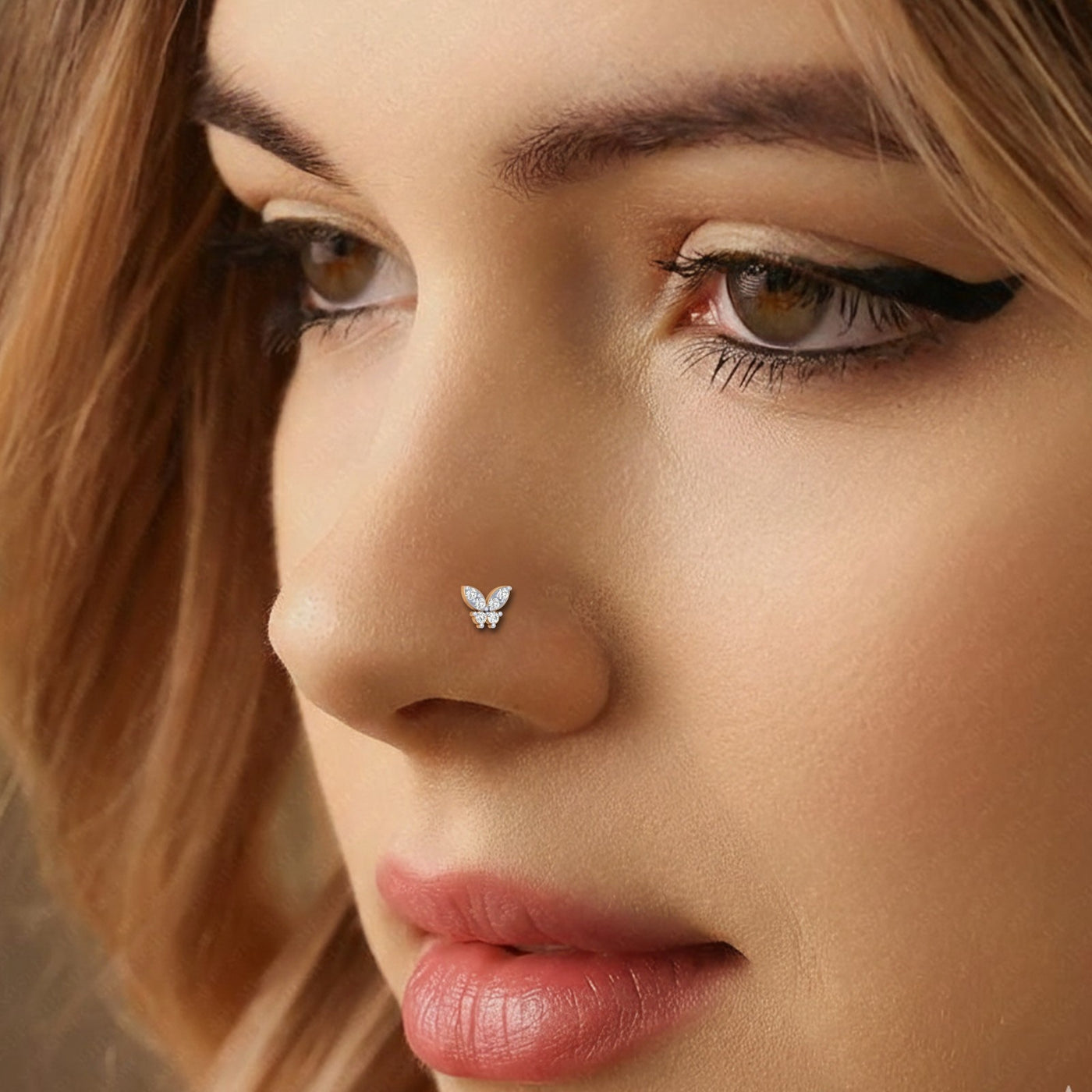 Close-up of a woman's face with a gold and diamond nose pinring.