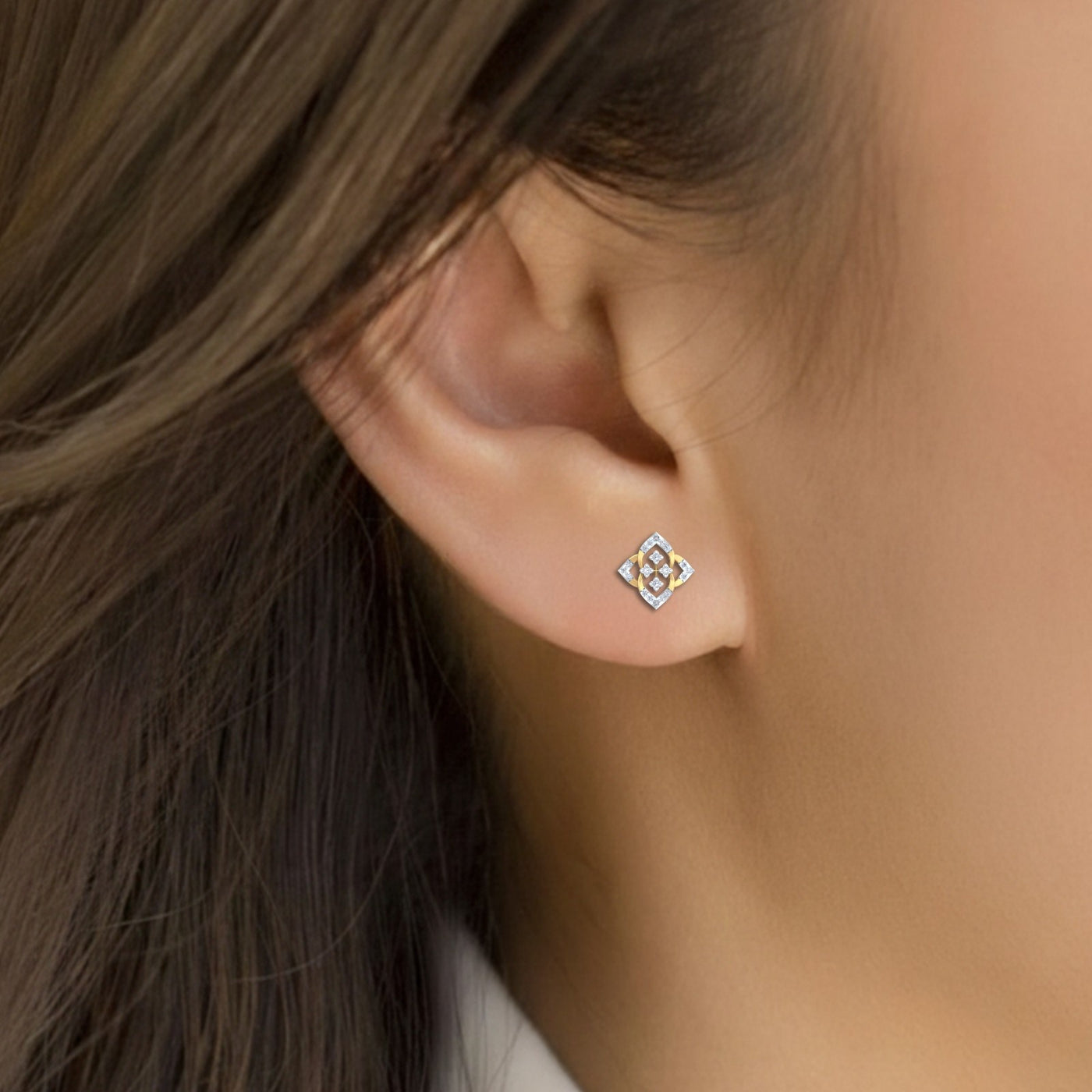 Close-up of an ear wearing a gold and diamond stud earring.