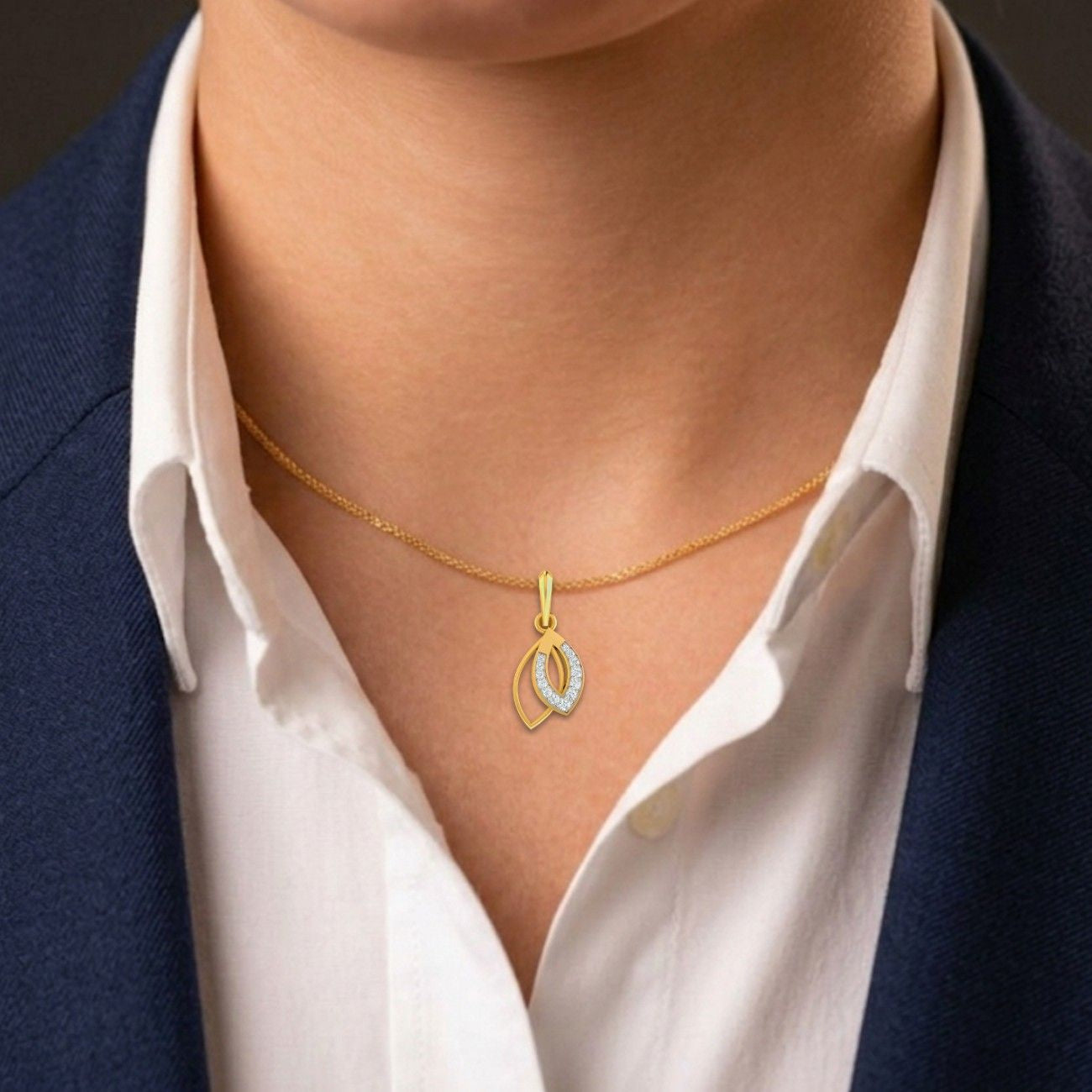 Gold necklace with a pendant worn by a person in a white shirt and dark blazer.