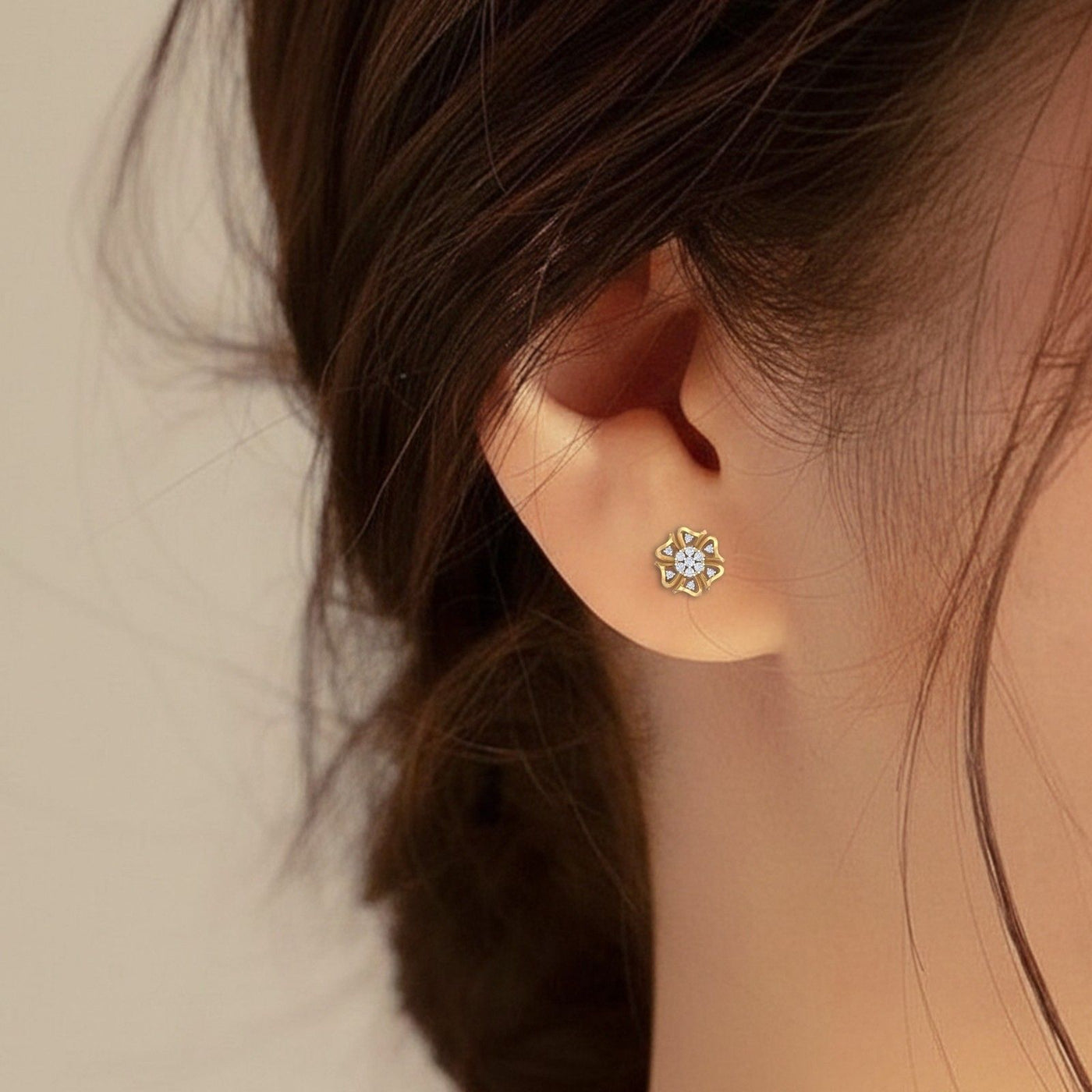 Close-up of an ear wearing a floral stud earring with a neutral background