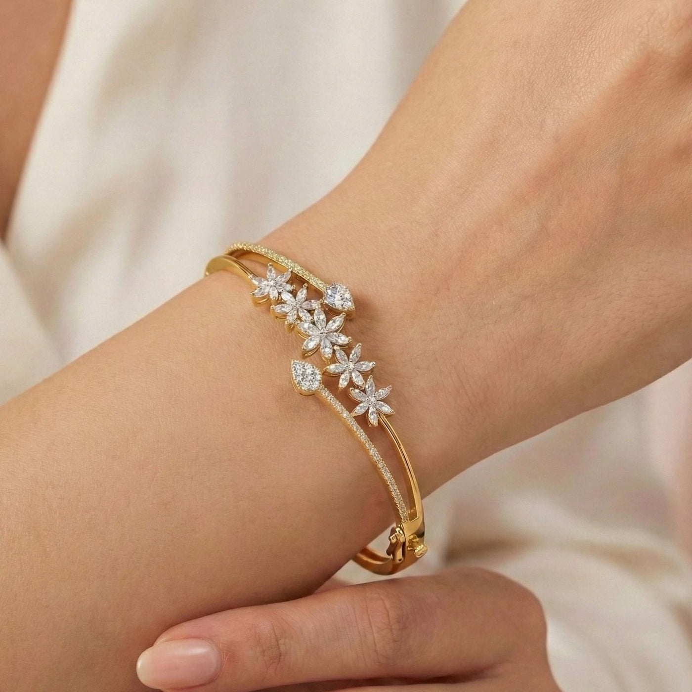 Gold bangle bracelet with cascading diamond floral clusters and a pavé-set band.
