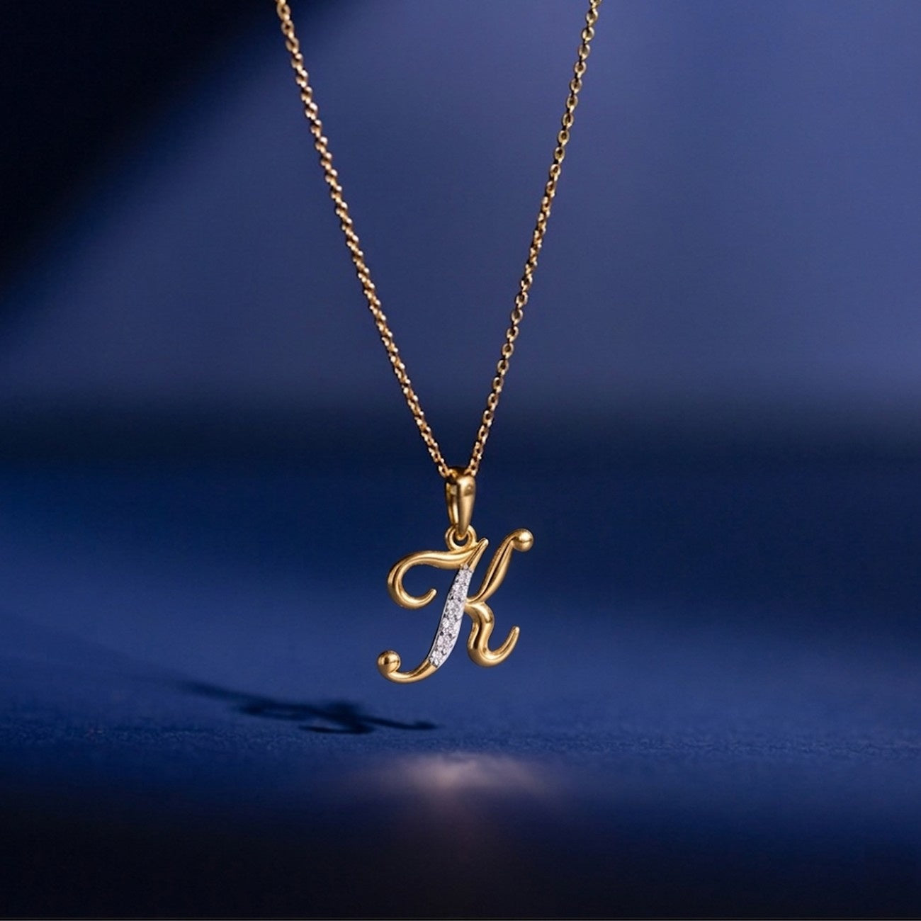 Gold necklace with a 'K' pendant on a blue background
