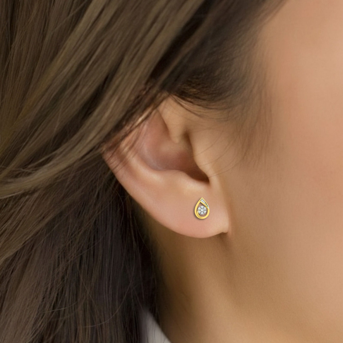 Close-up gold and diamond stud earring with teardrop-design on a white background.