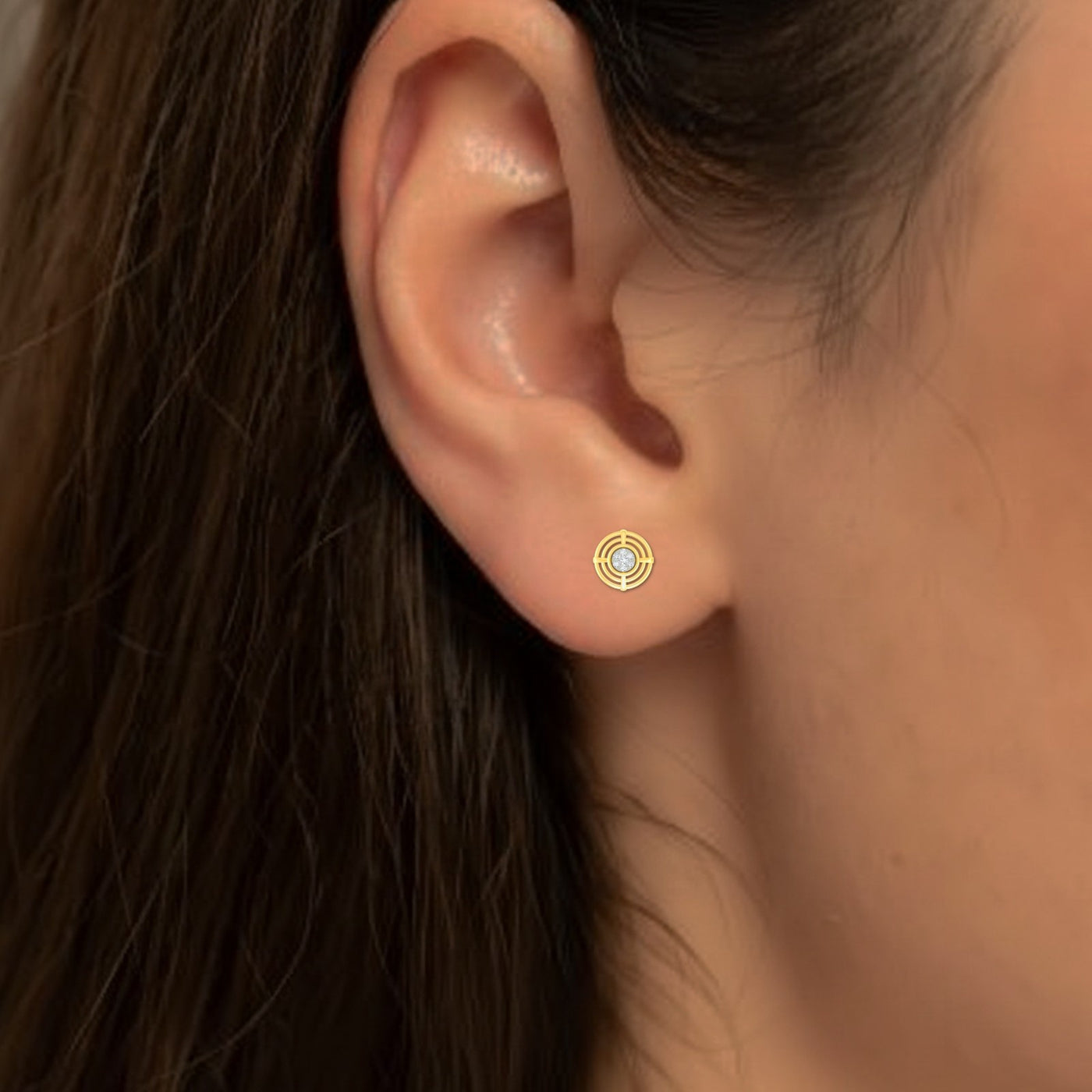 Close-up of an ear wearing a gold and diamond stud earring.