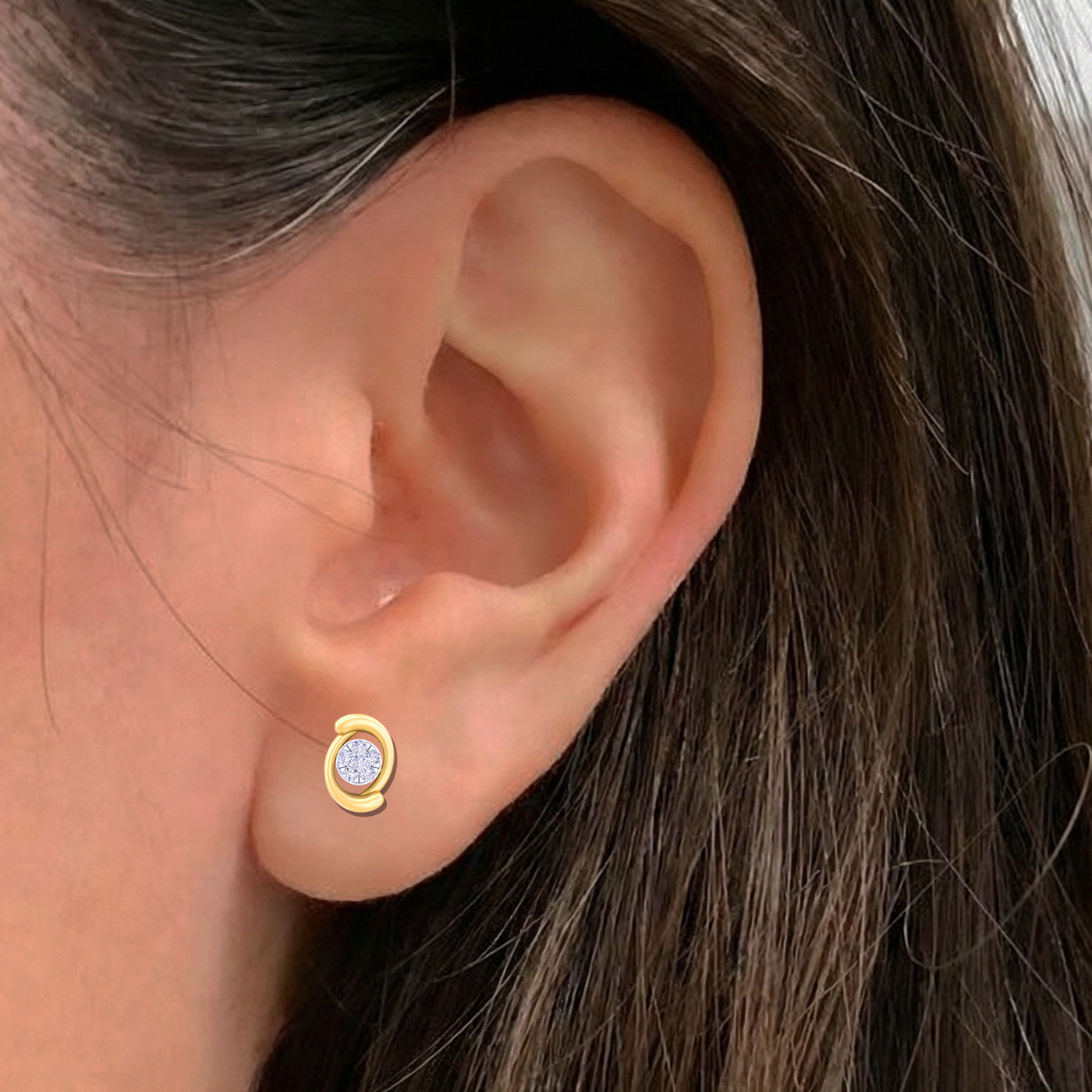 Close-up shot of a gold and diamond stud earring.