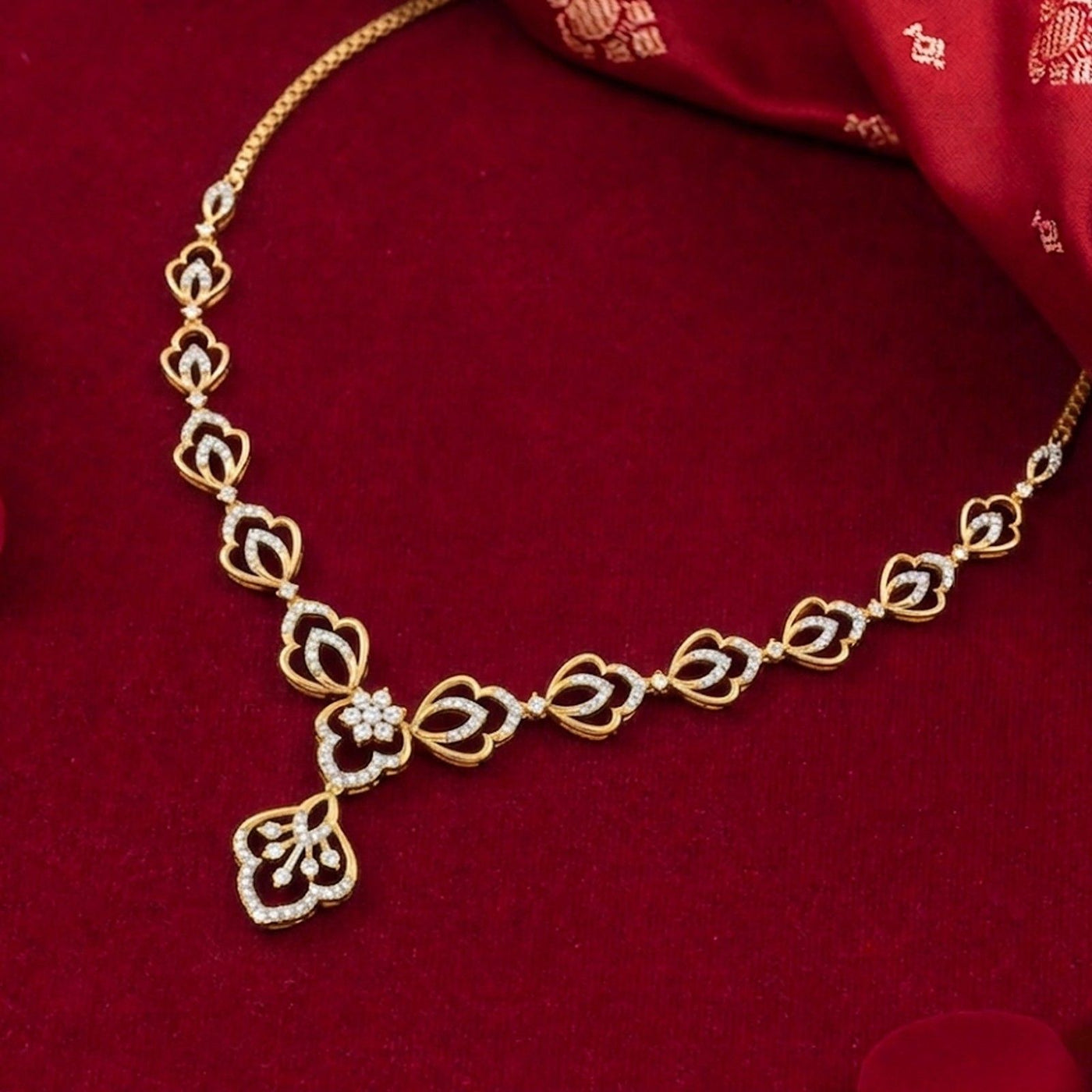 Gold and diamond necklace with a floral, displayed on a deep red velvet surface.