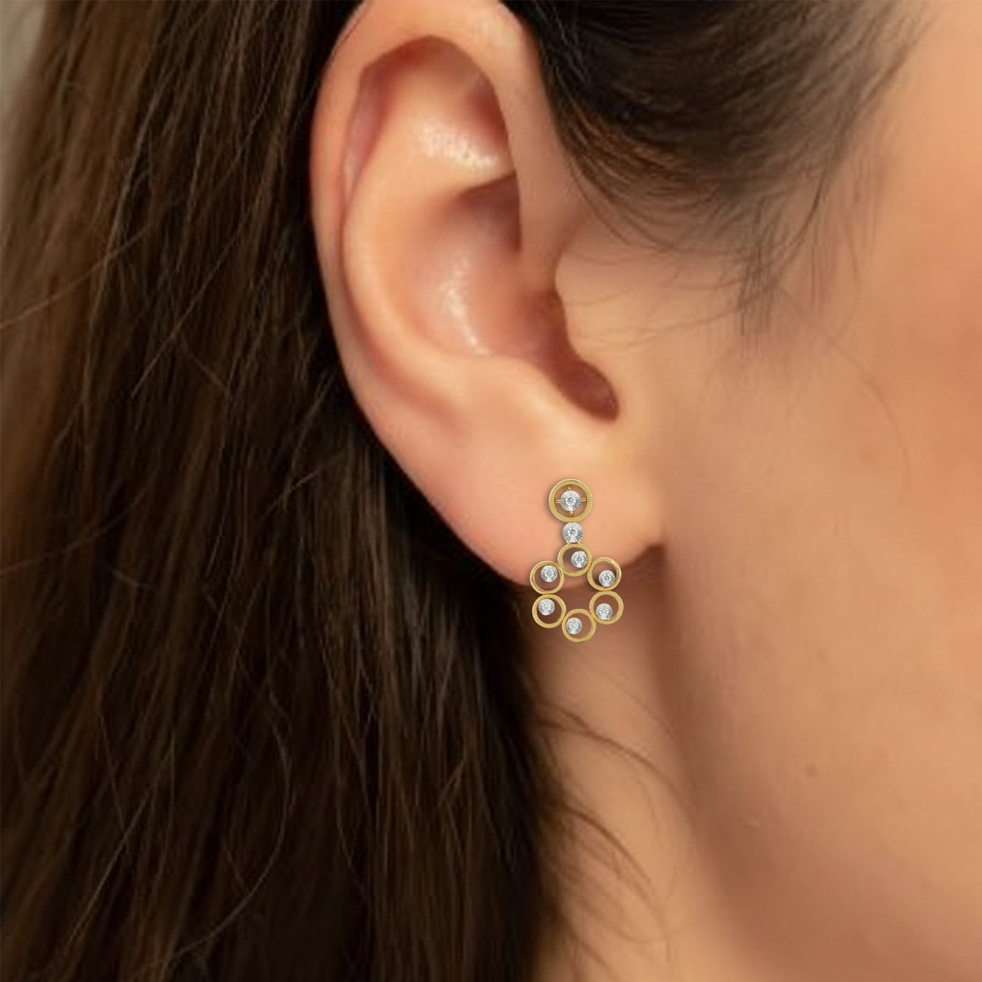 Close-up of an ear wearing a gold and diamond earring.