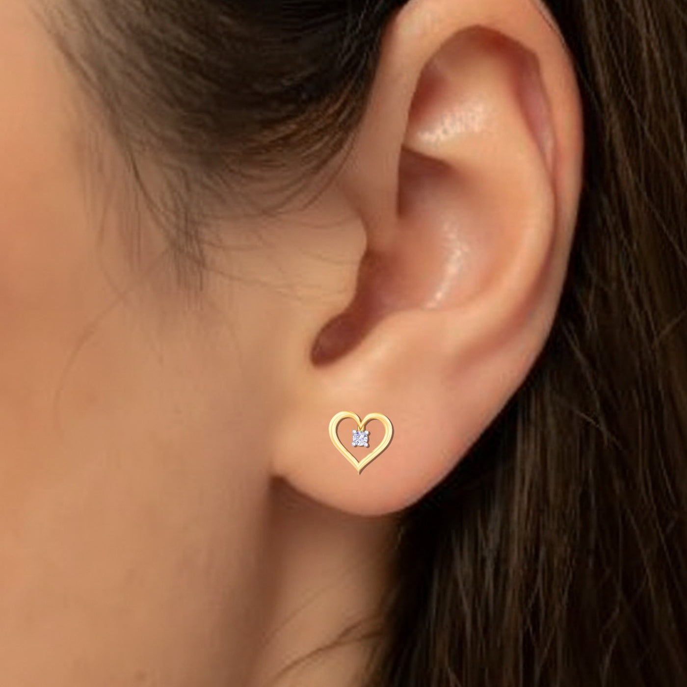 Close-up shot of gold heart-shaped earring with a central diamond.