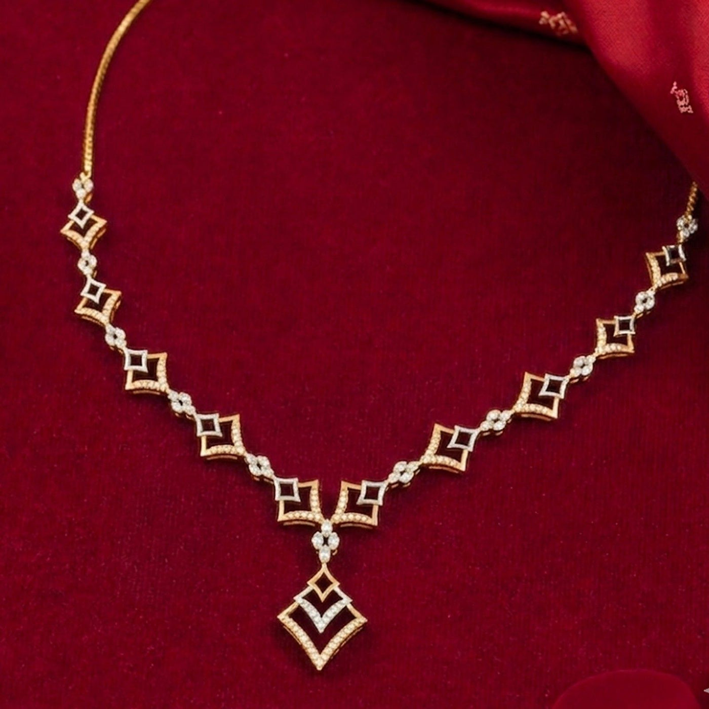 A gold and diamond necklace with a geometric diamond-patterned design, displayed on a deep red velvet background.