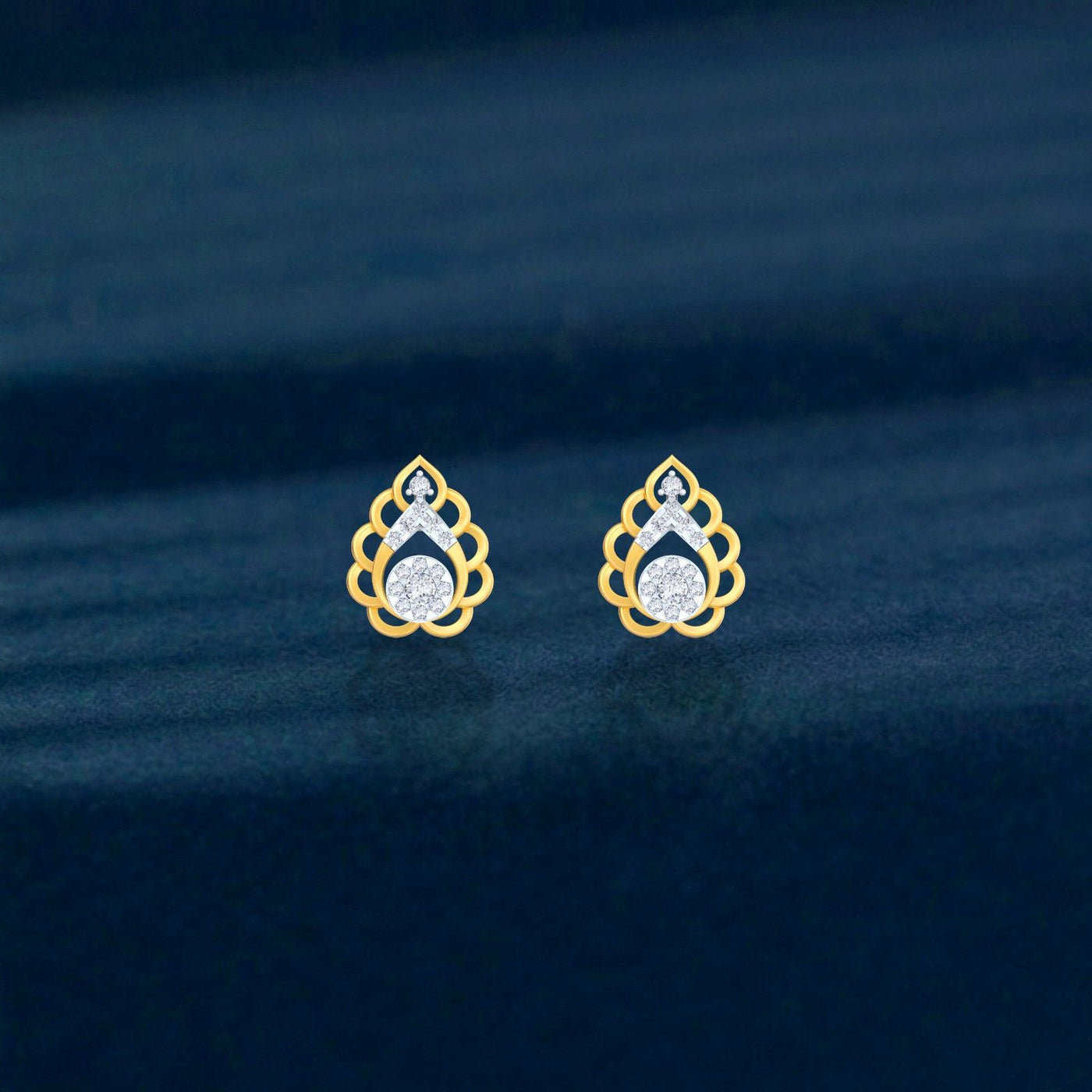 Gold and diamond stud earring with teardrop-design on a blue surface.
