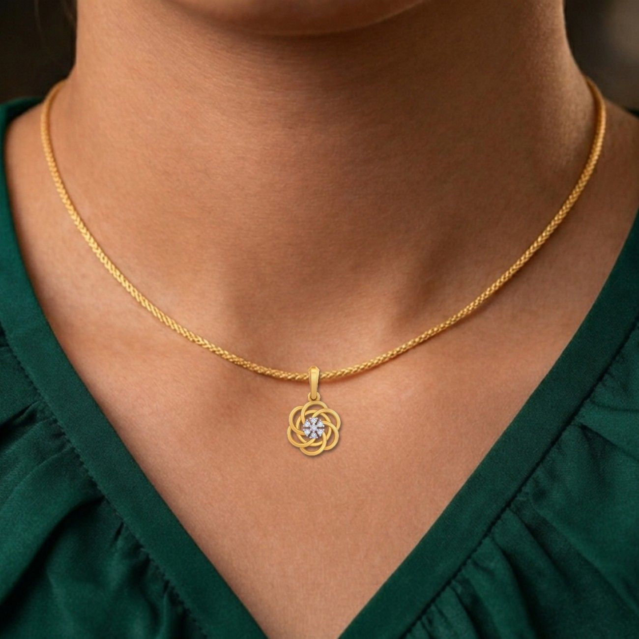Gold necklace with a pendant worn by a person in a green top.