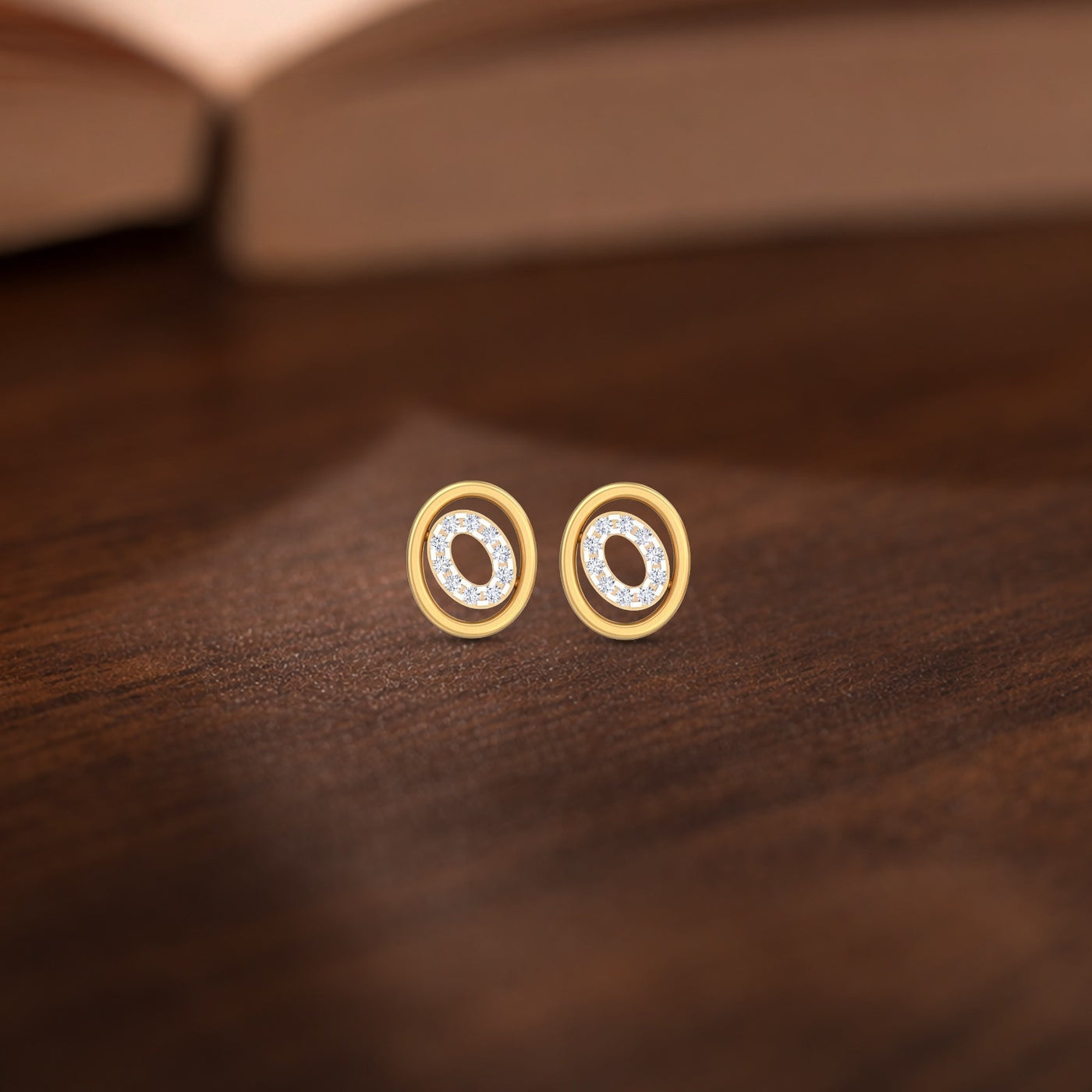 Gold and diamond stud earrings with circular design on a wooden surface