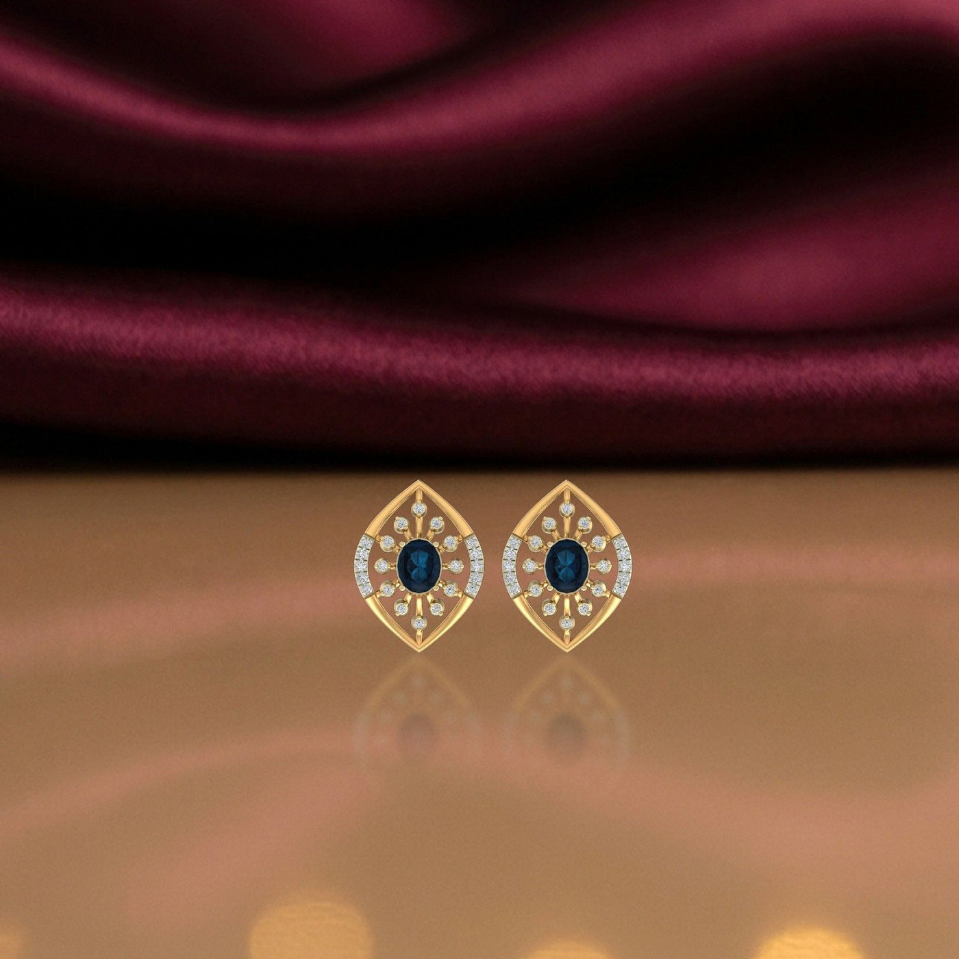 Gold and diamond stud earring with sapphire on a reflective background.