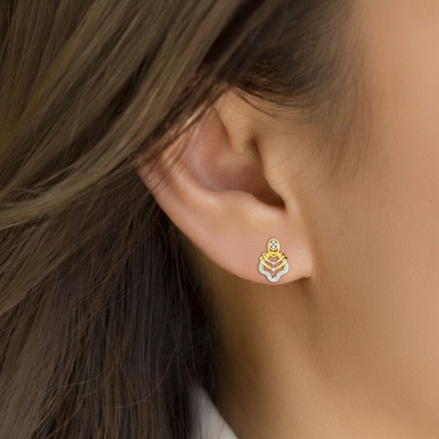 Close-up of an ear wearing a gold and diamond stud earrings.