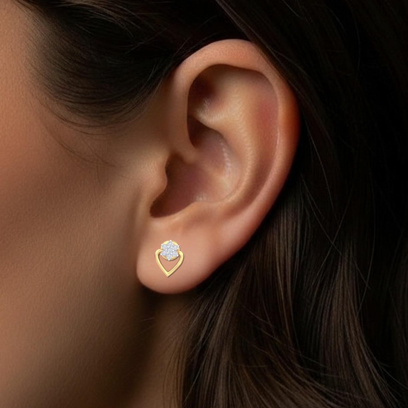 Close-up of an ear wearing a gold heart-shaped earring with a central diamond.