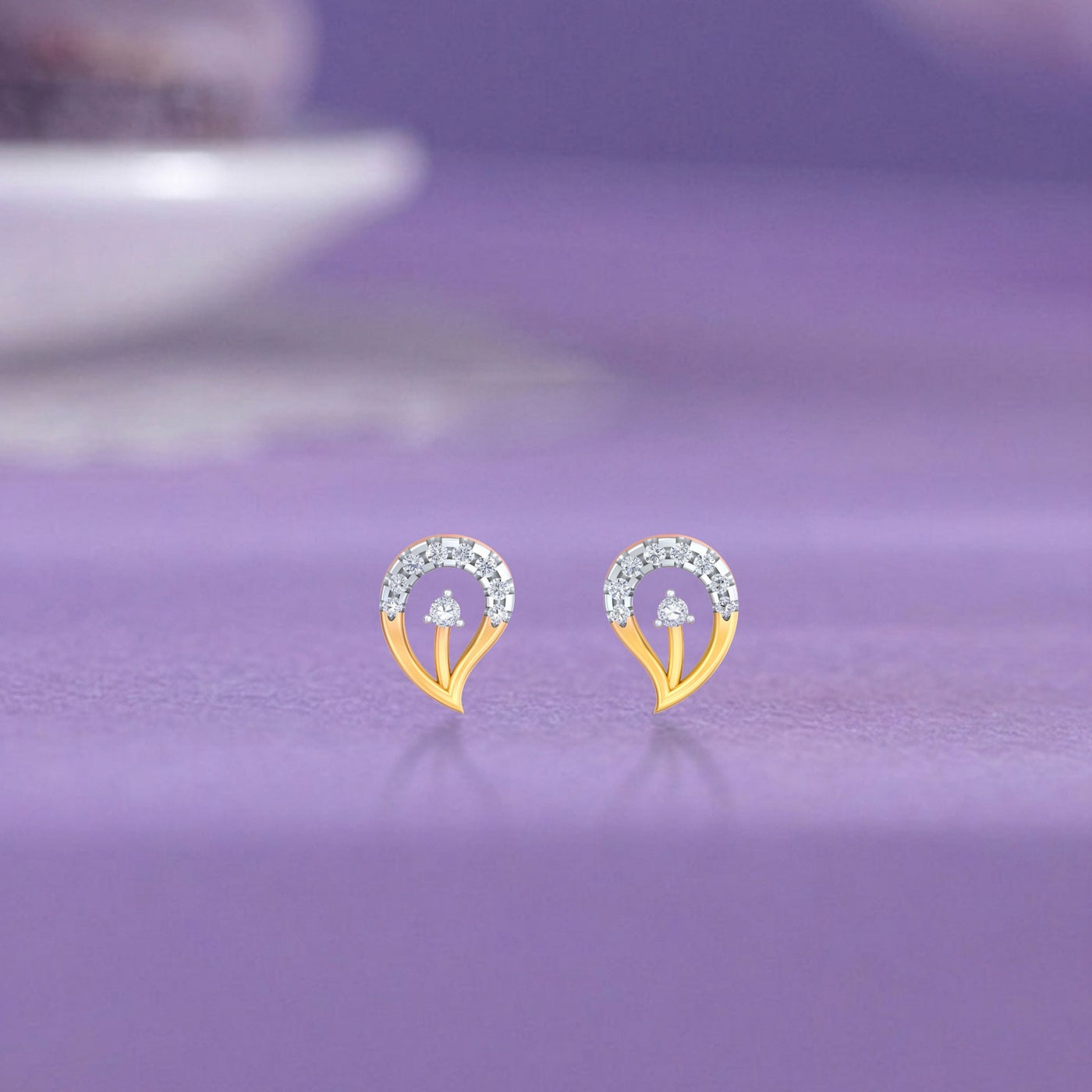 Gold and diamond stud earring with leaf-design on a background.