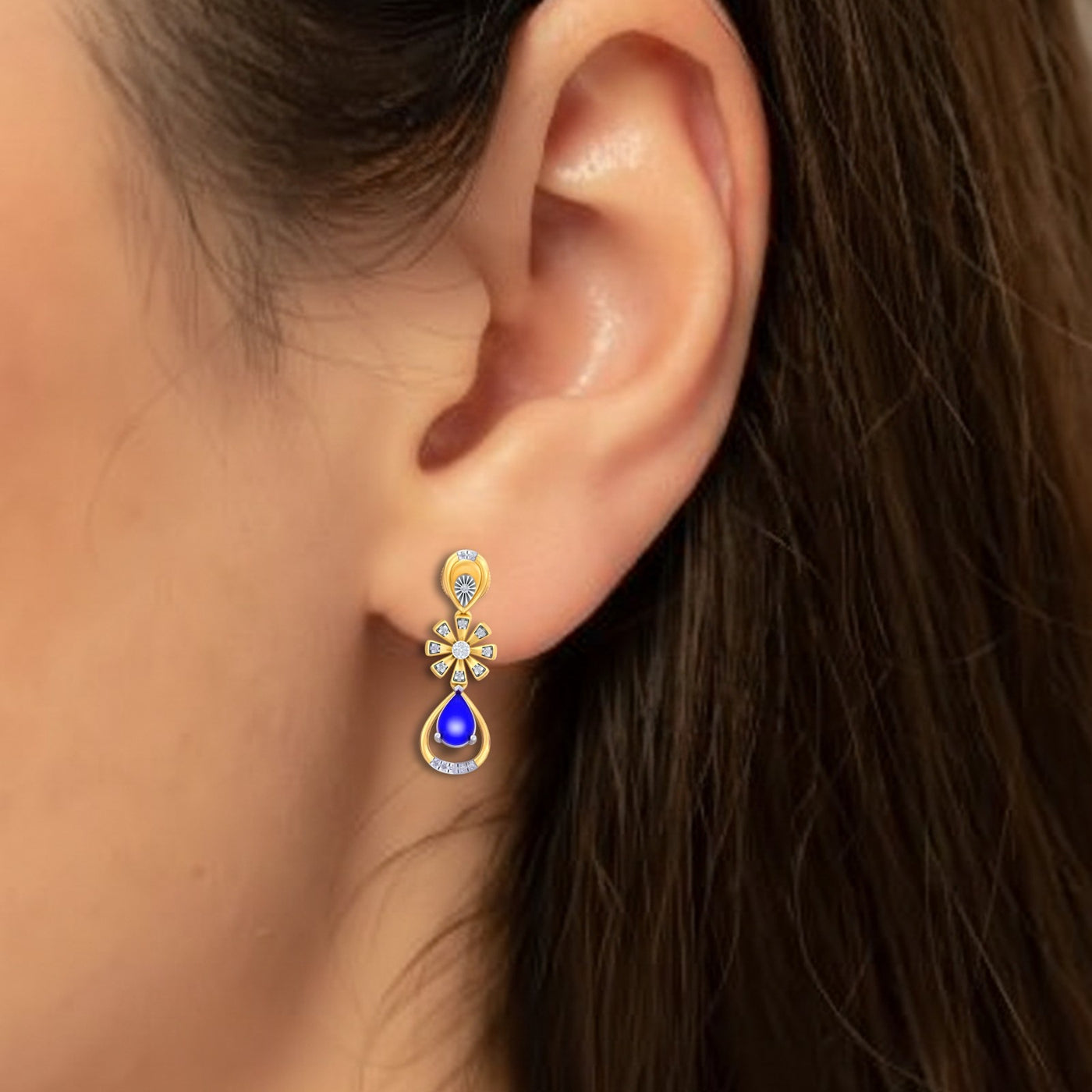 Close-up shot of a gold and diamond drop earring with gemstone.