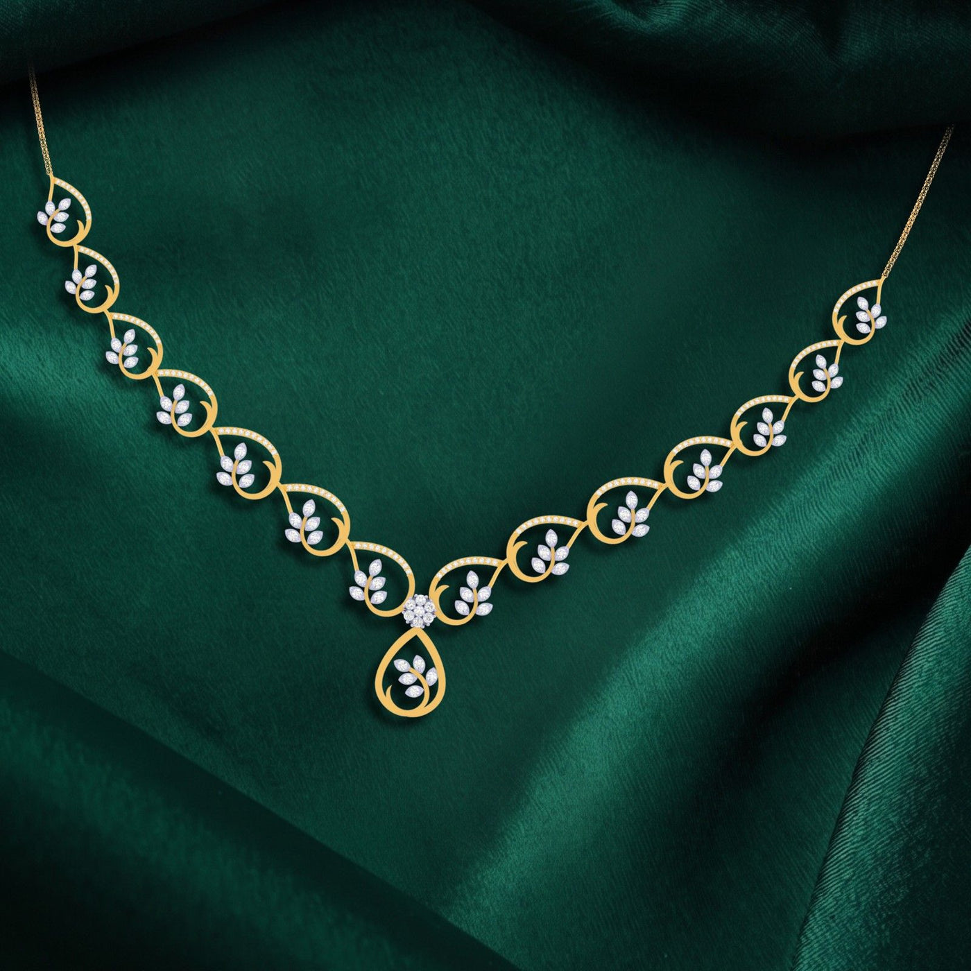 A gold and diamond necklace with a leaf motif, displayed on a draped dark green satin fabric.