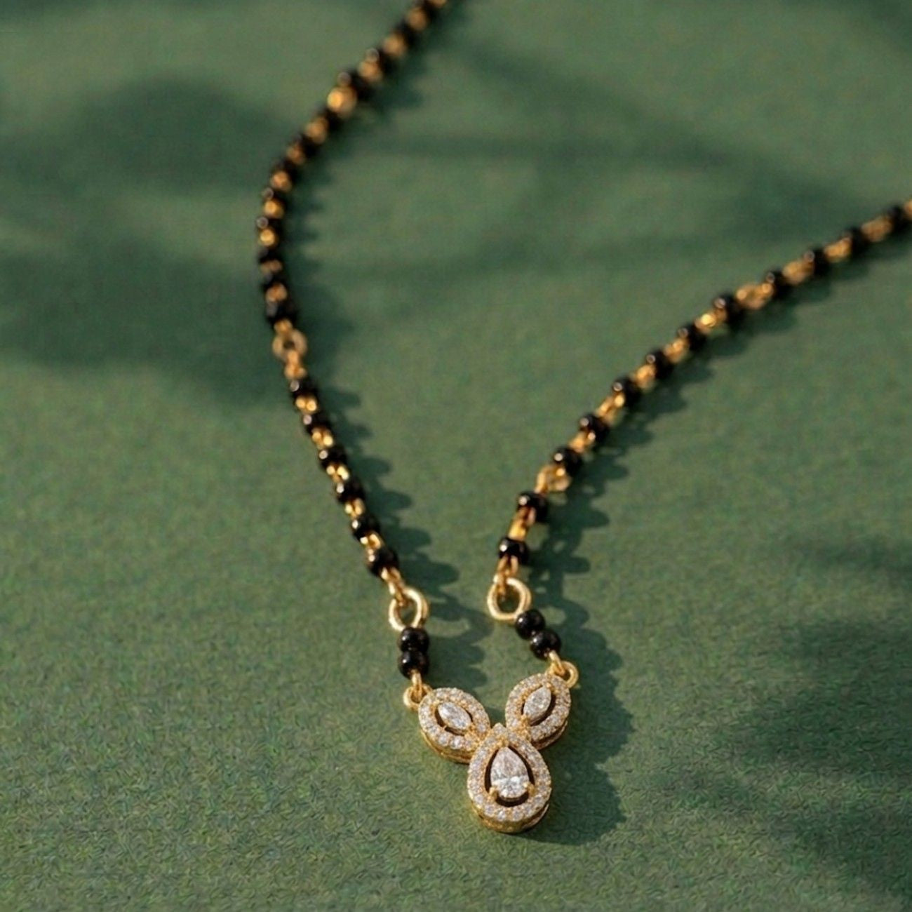 gold and diamond modern mangalsutra on green background