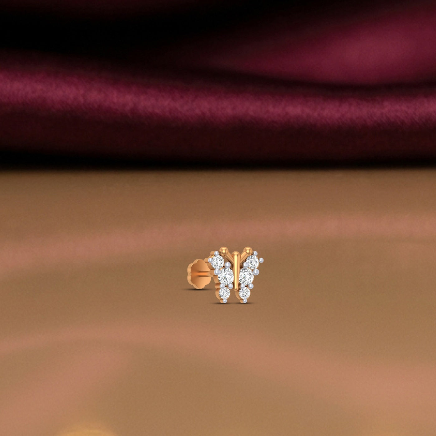 Gold and diamond stud nose pin on a brown fabric background