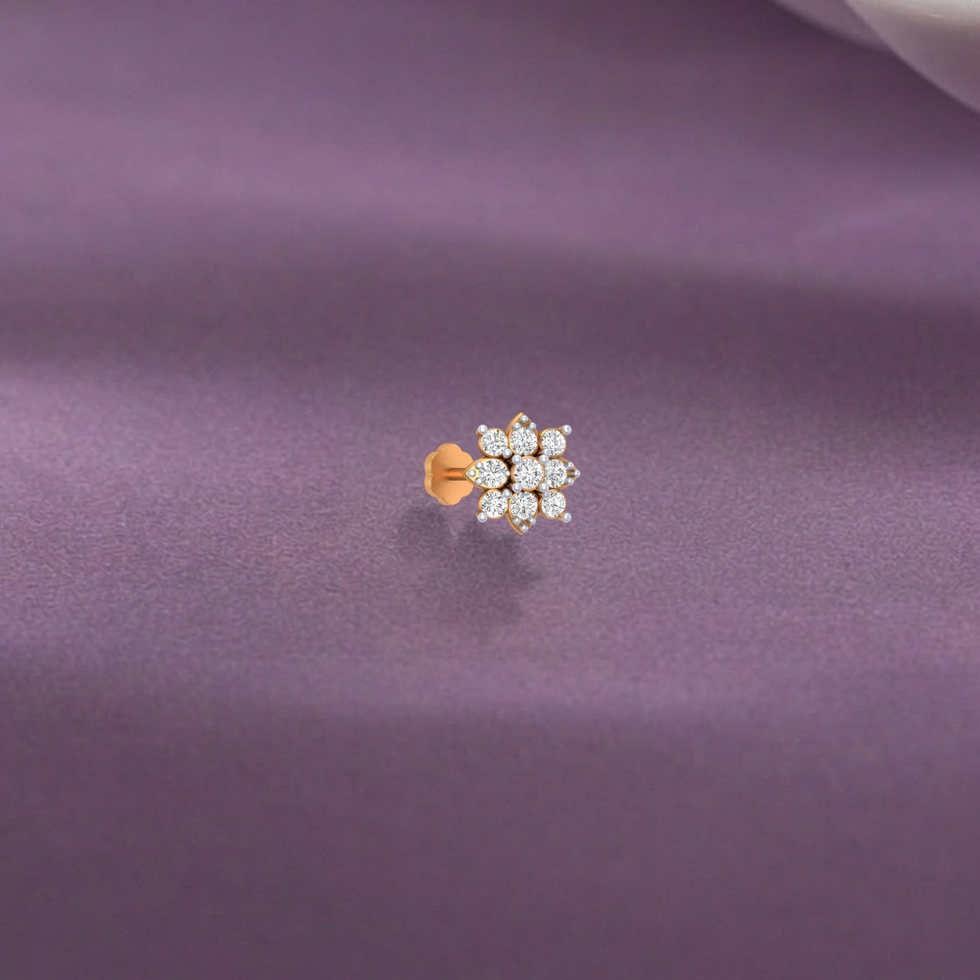 Yellow gold and diamond stud nosepin on a purple fabric background